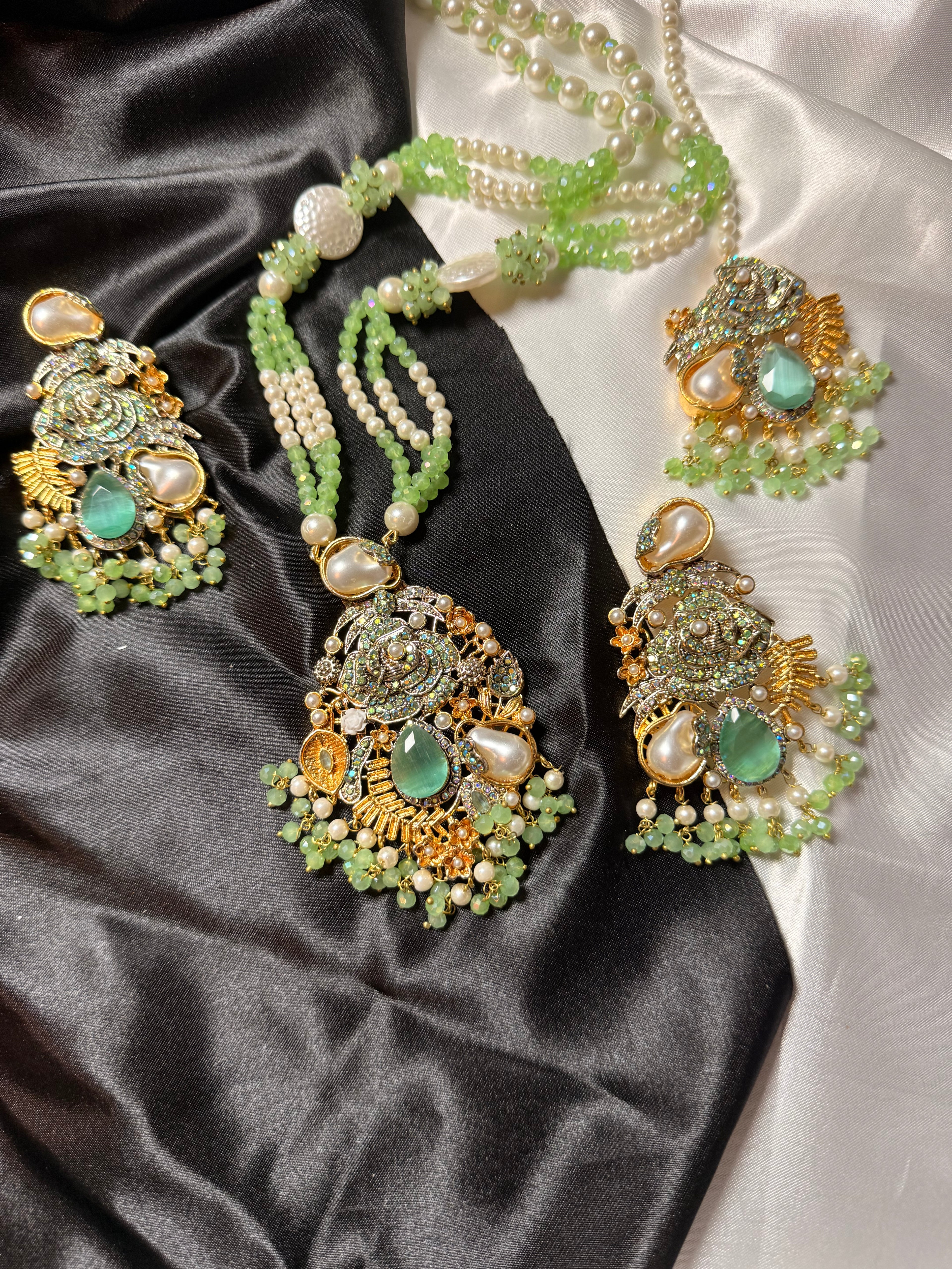 Ornate jewelry set with green and gold elements on a satin surface