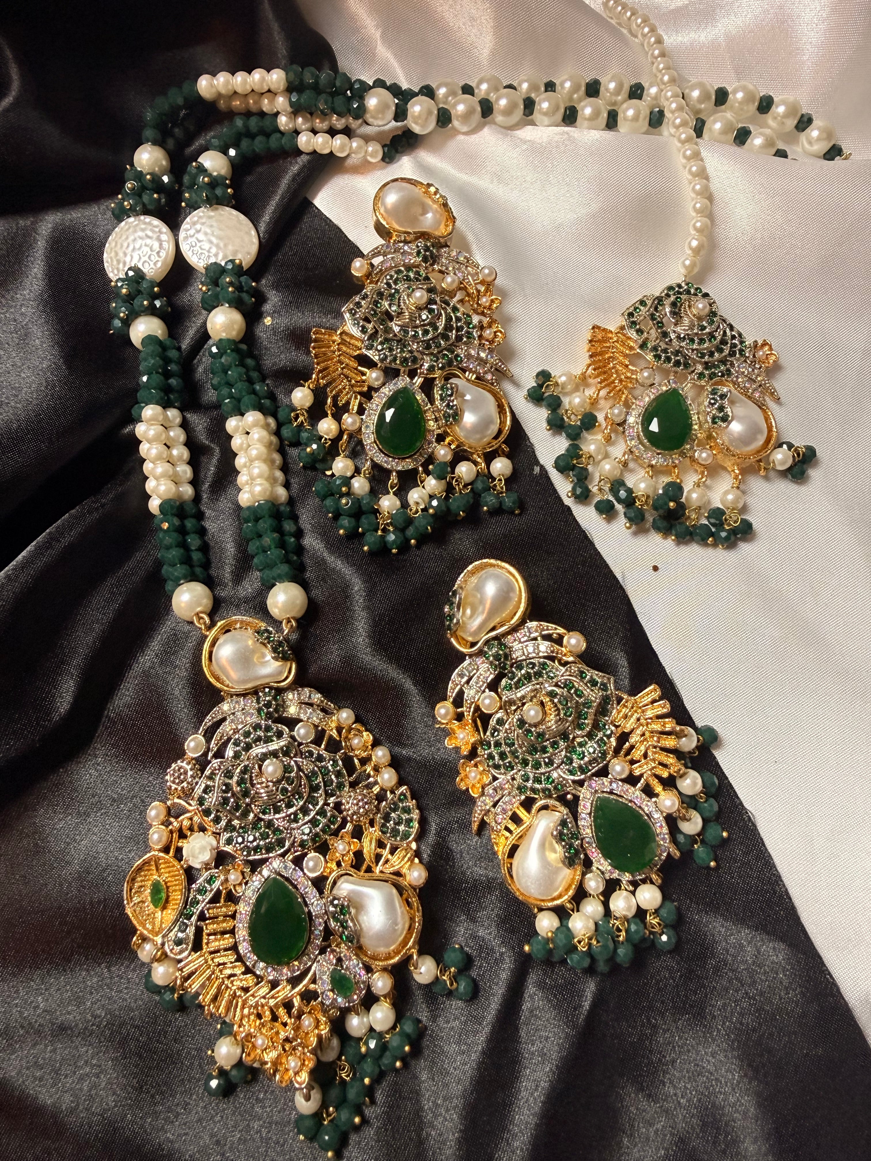 Ornate jewelry set with green and gold stones on a satin surface