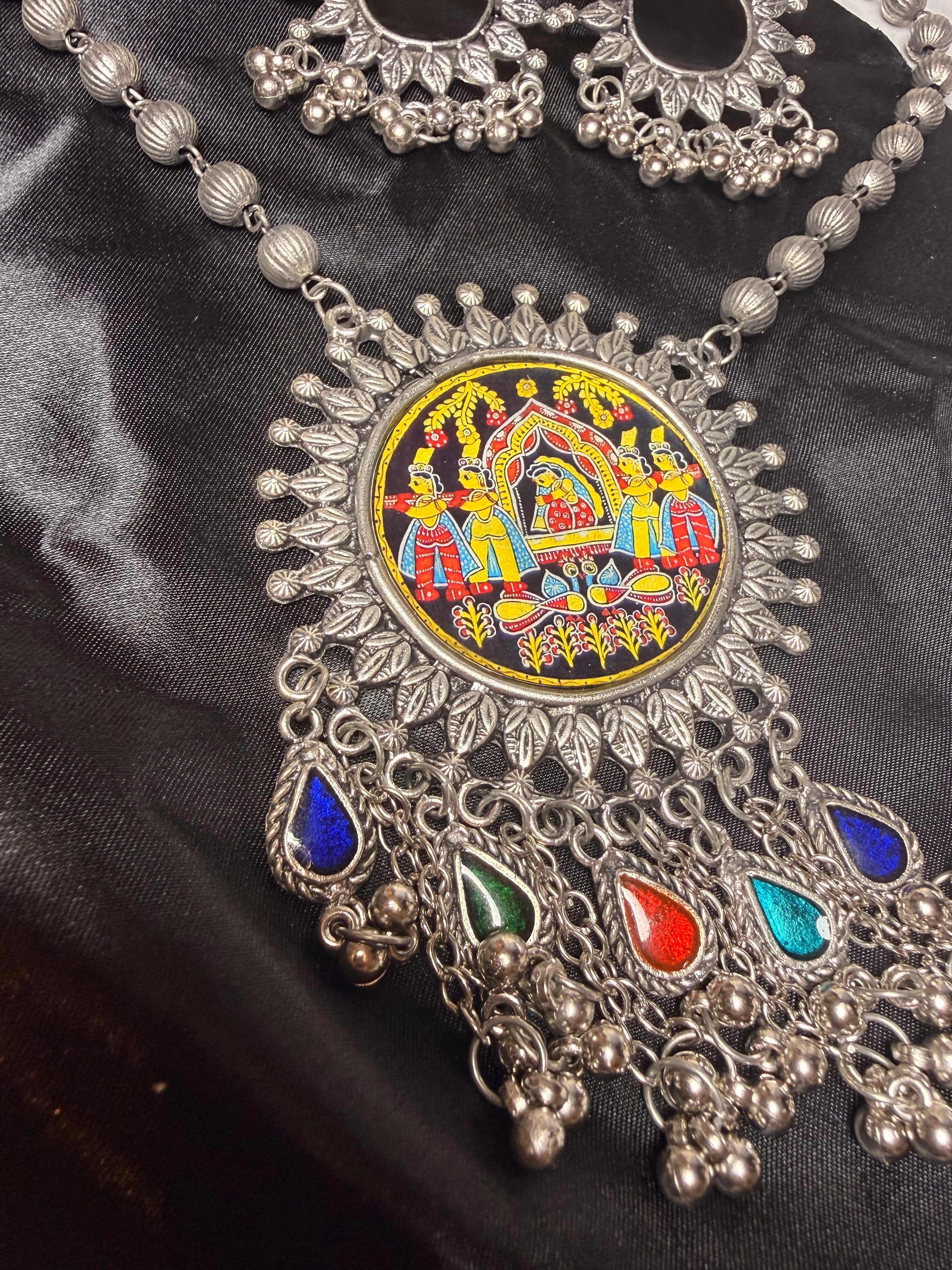 Decorative silver necklace with colorful gemstones on a black fabric background
