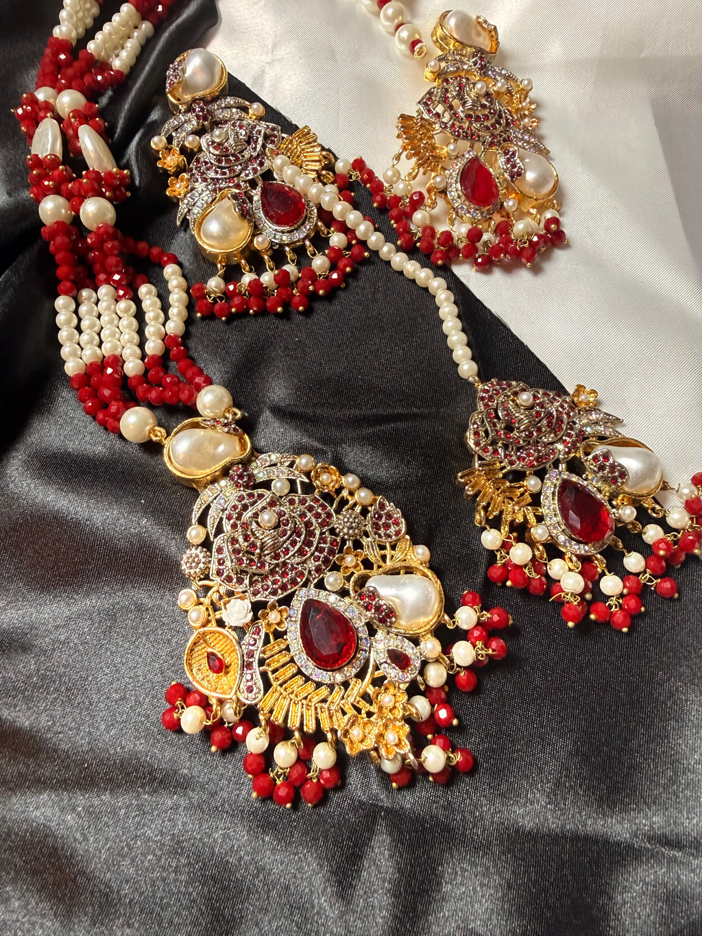 Ornate jewelry set with red and gold accents on a black fabric background
