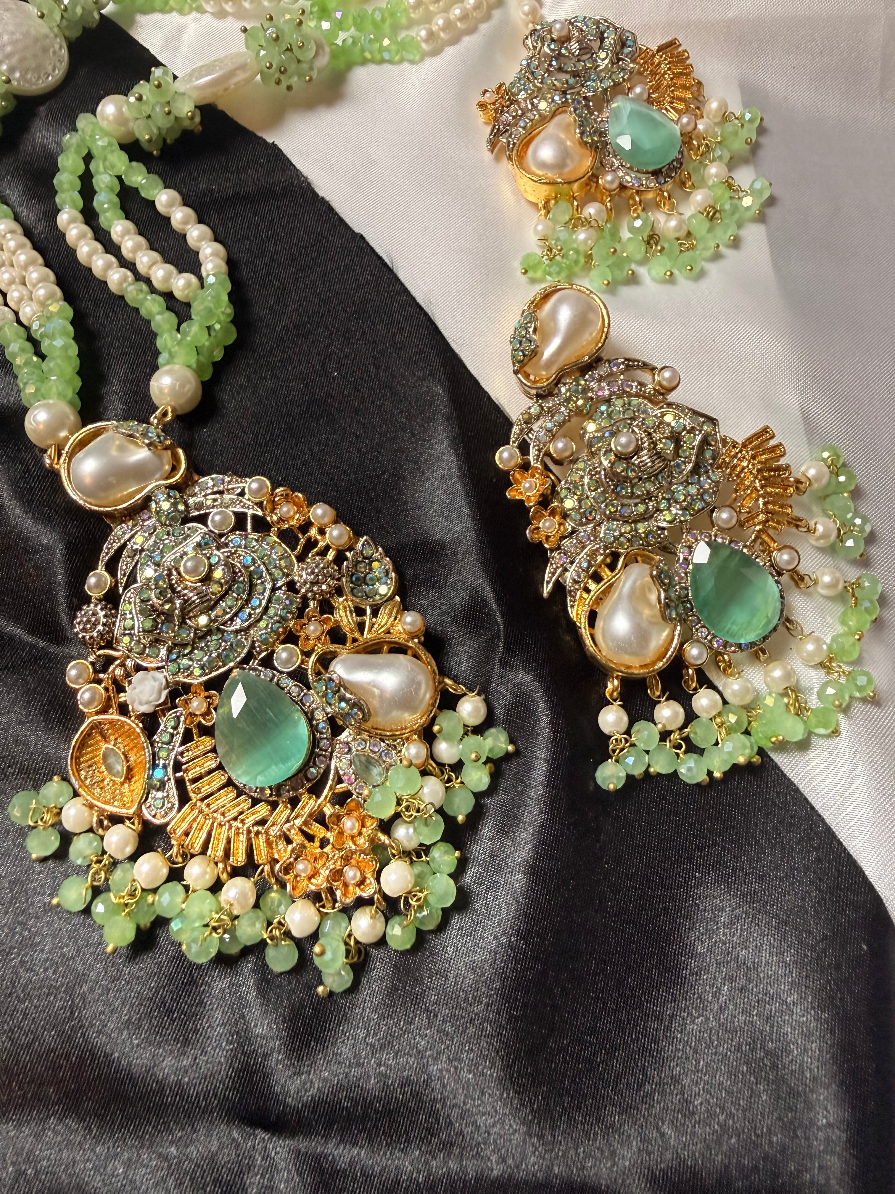 Ornate jewelry set with green and gold elements on a black and white fabric background