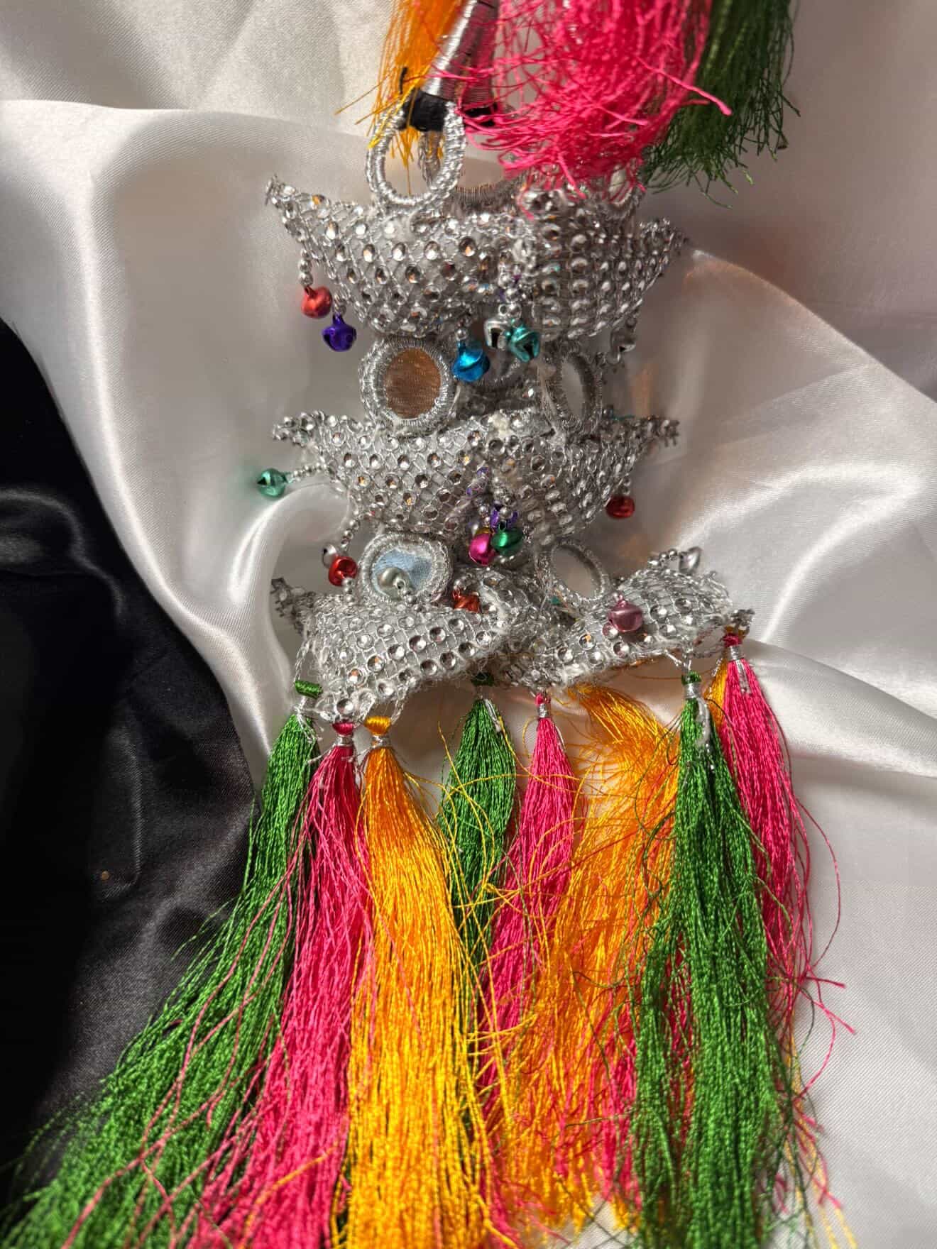 Decorative star ornament with colorful tassels on a white fabric background