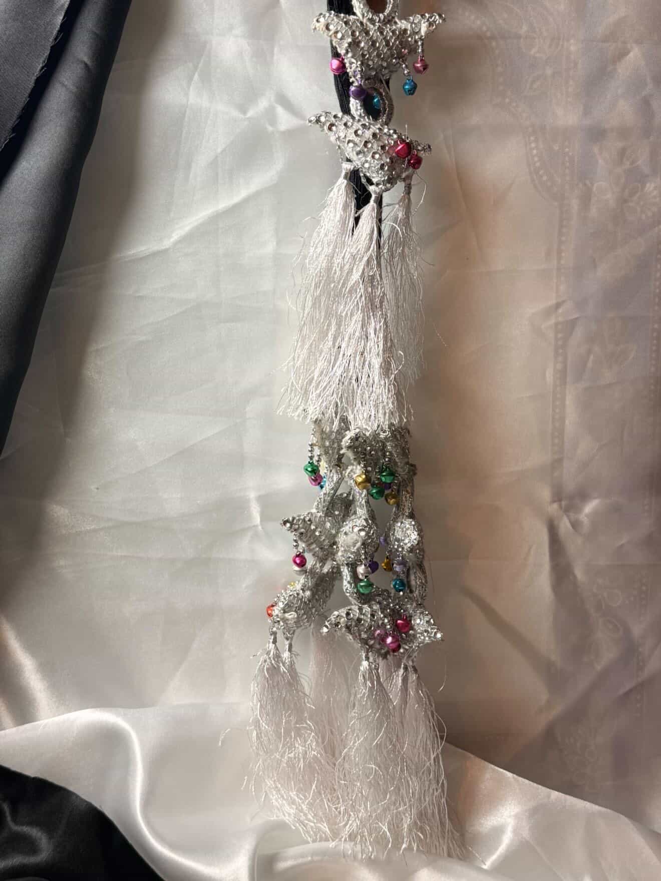 Decorative hanging with tassels and beads on a textured white background