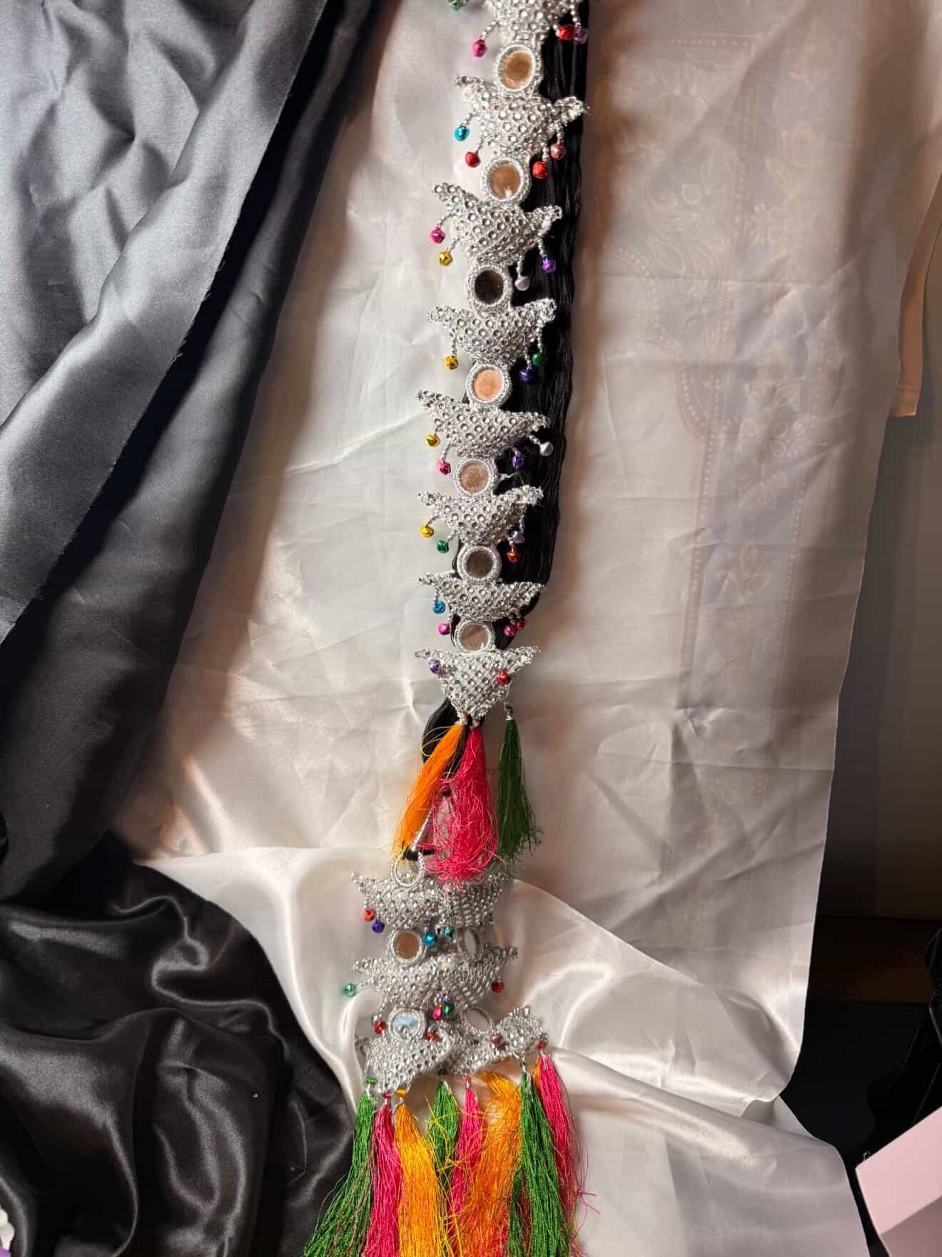 Decorative belt with colorful tassels and star-shaped embellishments on a plain background