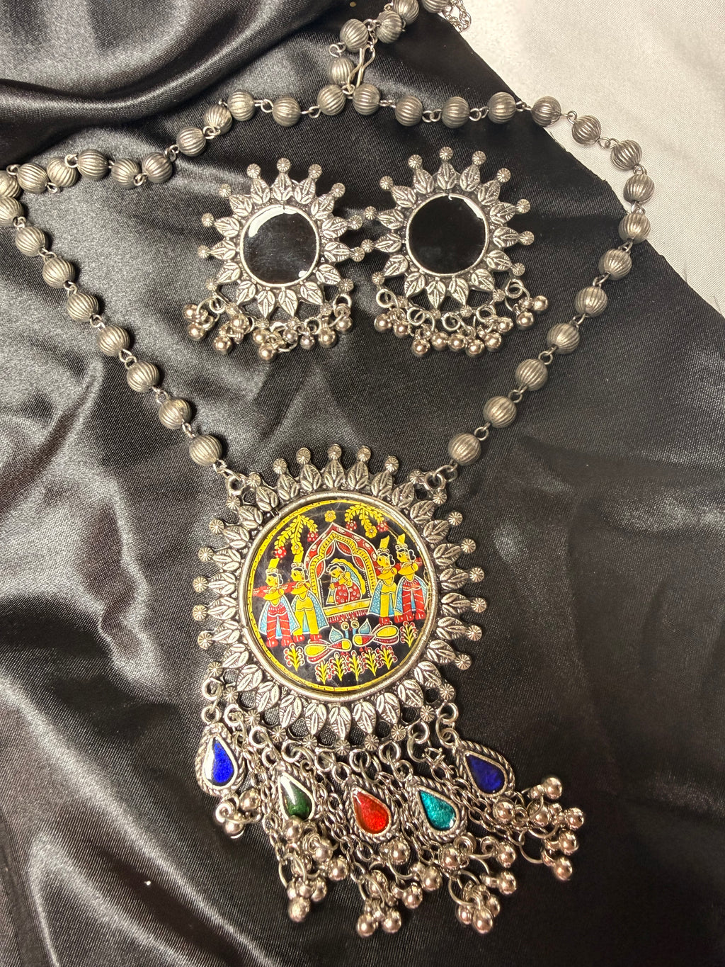 Ornate necklace with colorful pendant on a dark fabric background