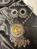 Ornate necklace with colorful pendant on a dark fabric background