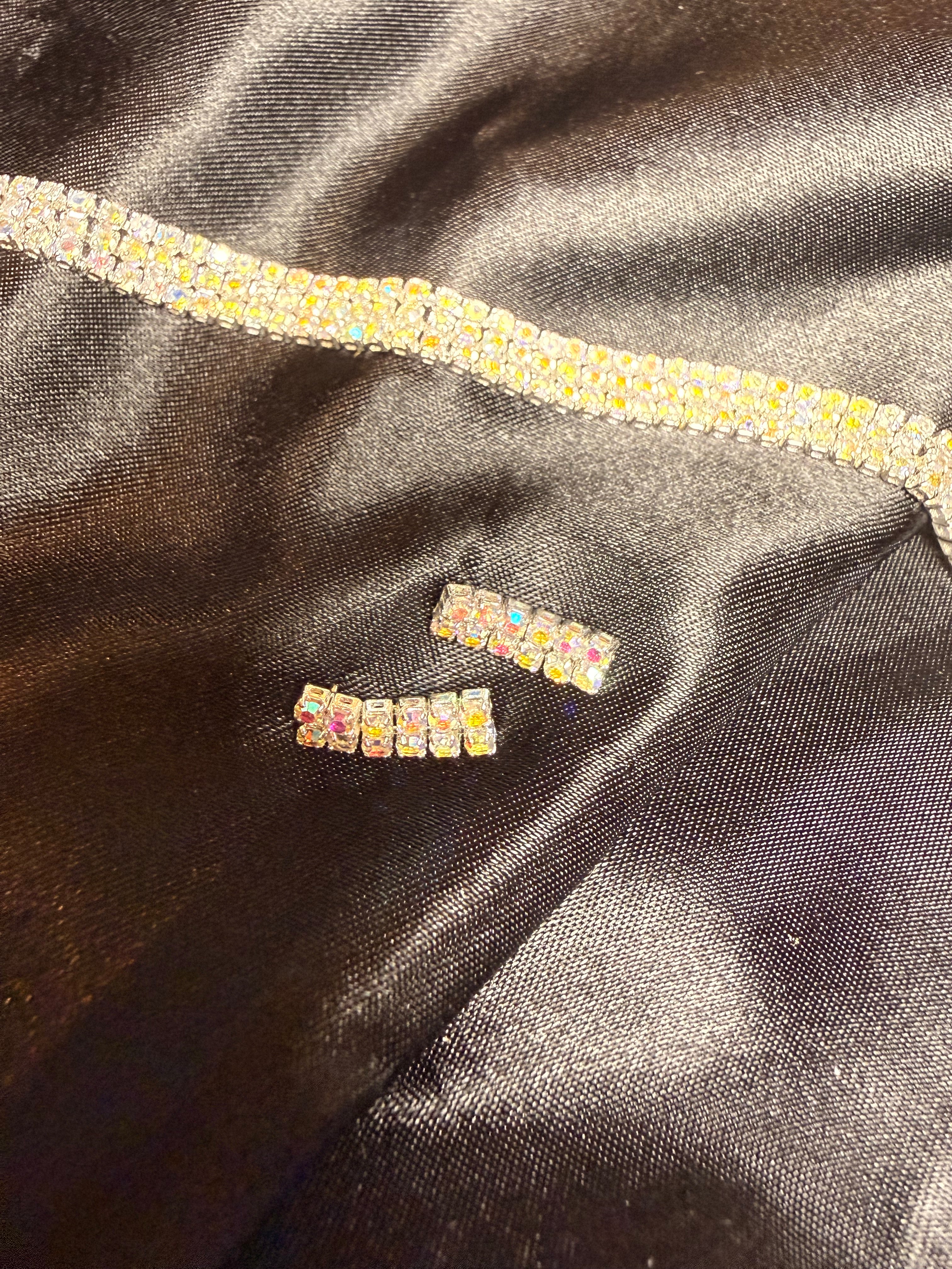 Pair of rhinestone earrings on a black satin surface