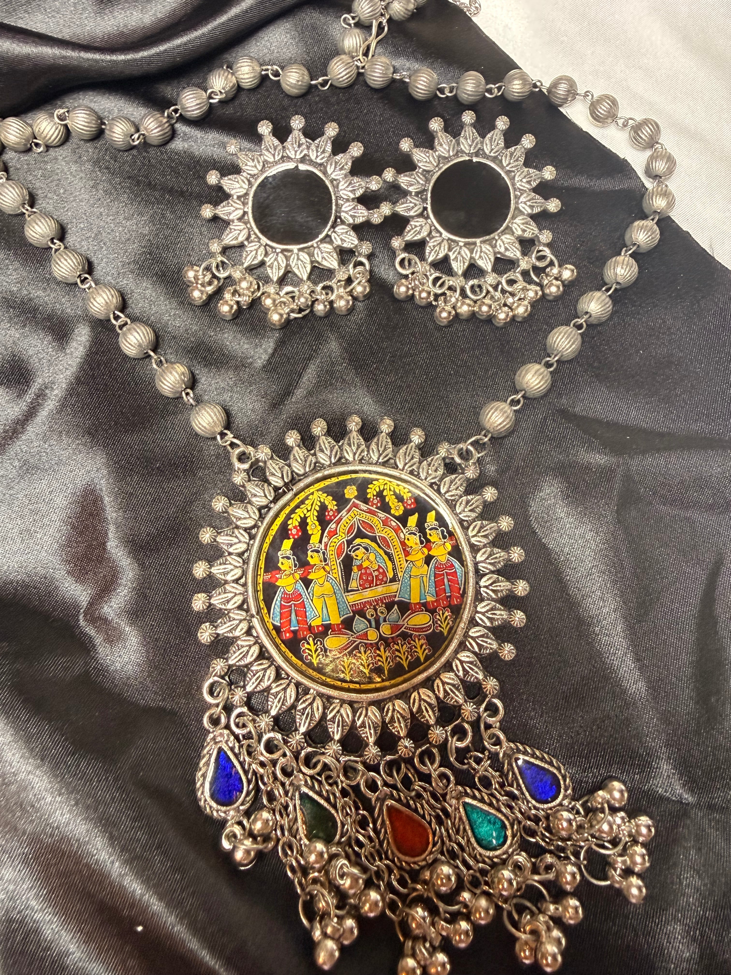 Ornate necklace with colorful central design on a dark fabric background
