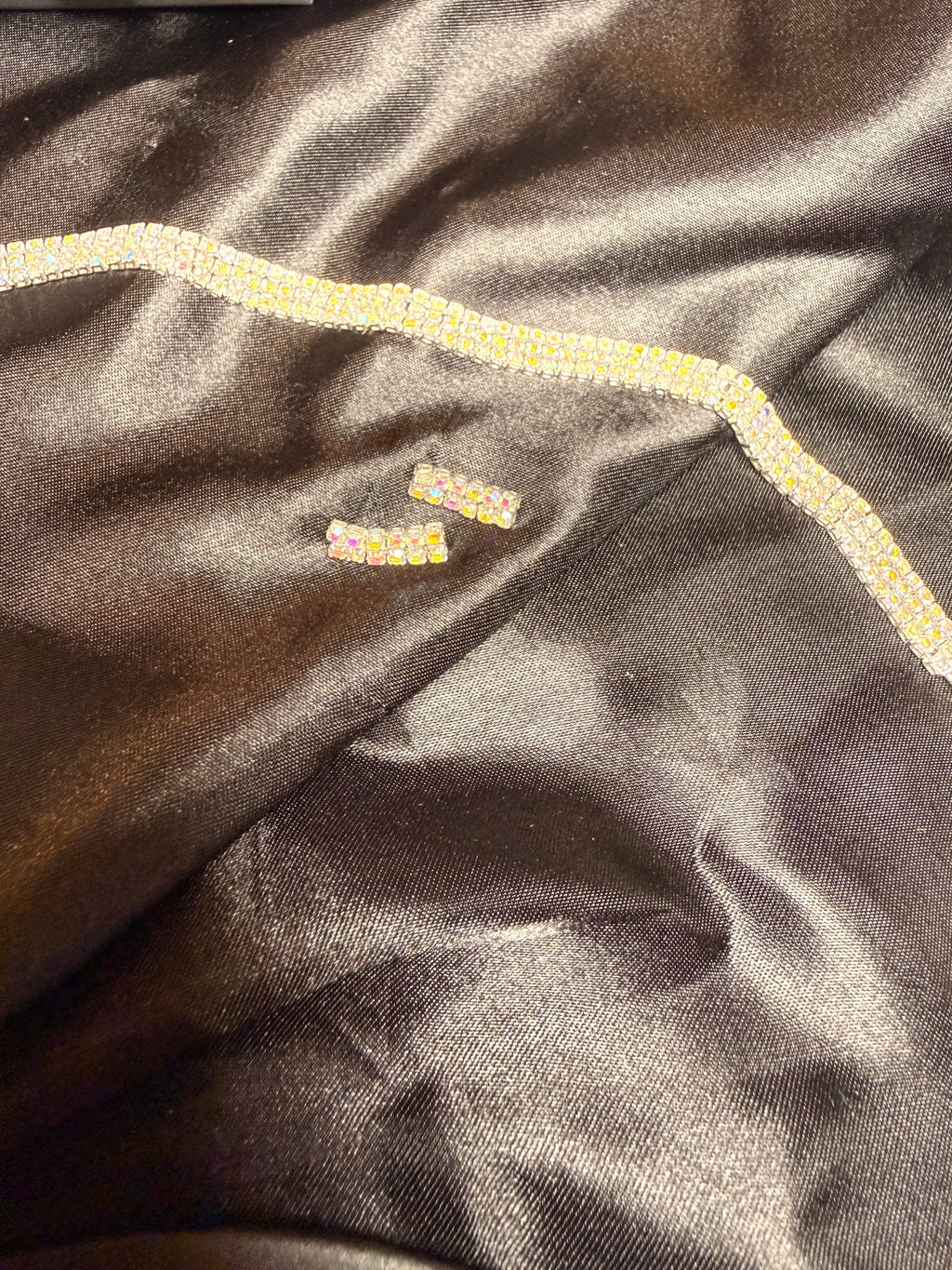 Close-up of dark fabric with decorative trim and embroidered text.