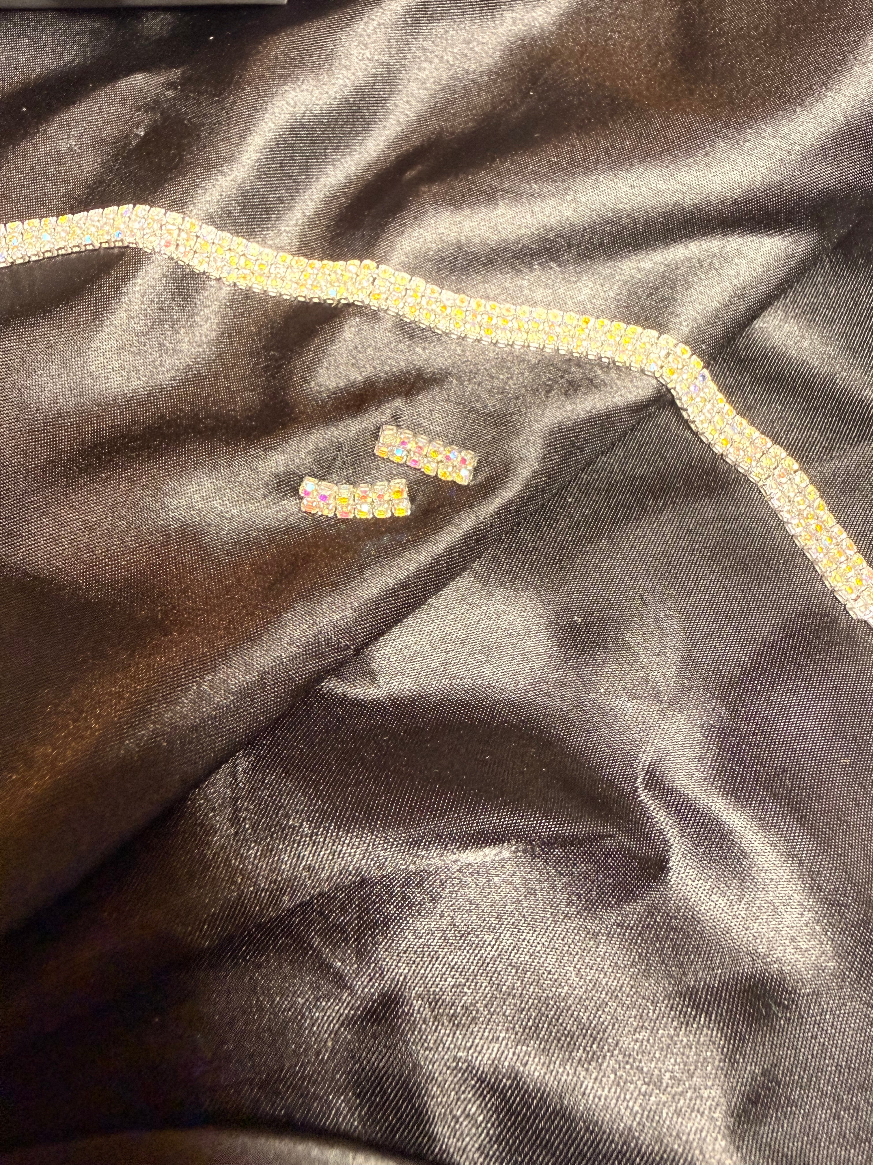 Close-up of dark fabric with decorative trim and embroidered text.