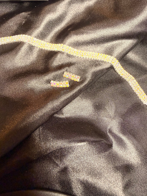 Close-up of dark fabric with decorative trim and embroidered text.