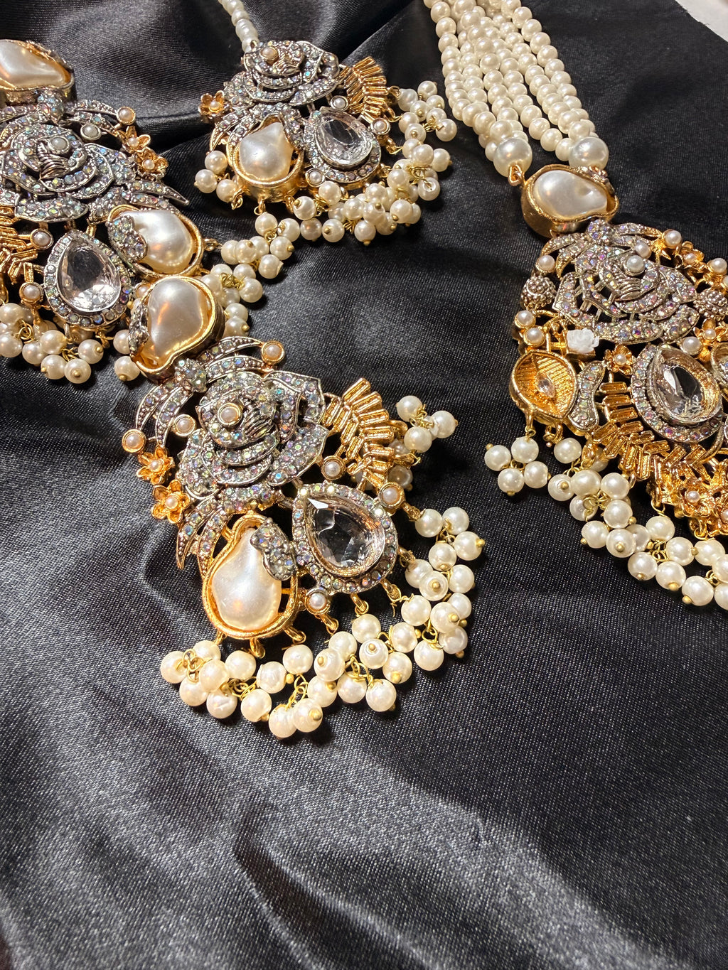 Ornate jewelry set with pearls and crystals on a dark fabric background