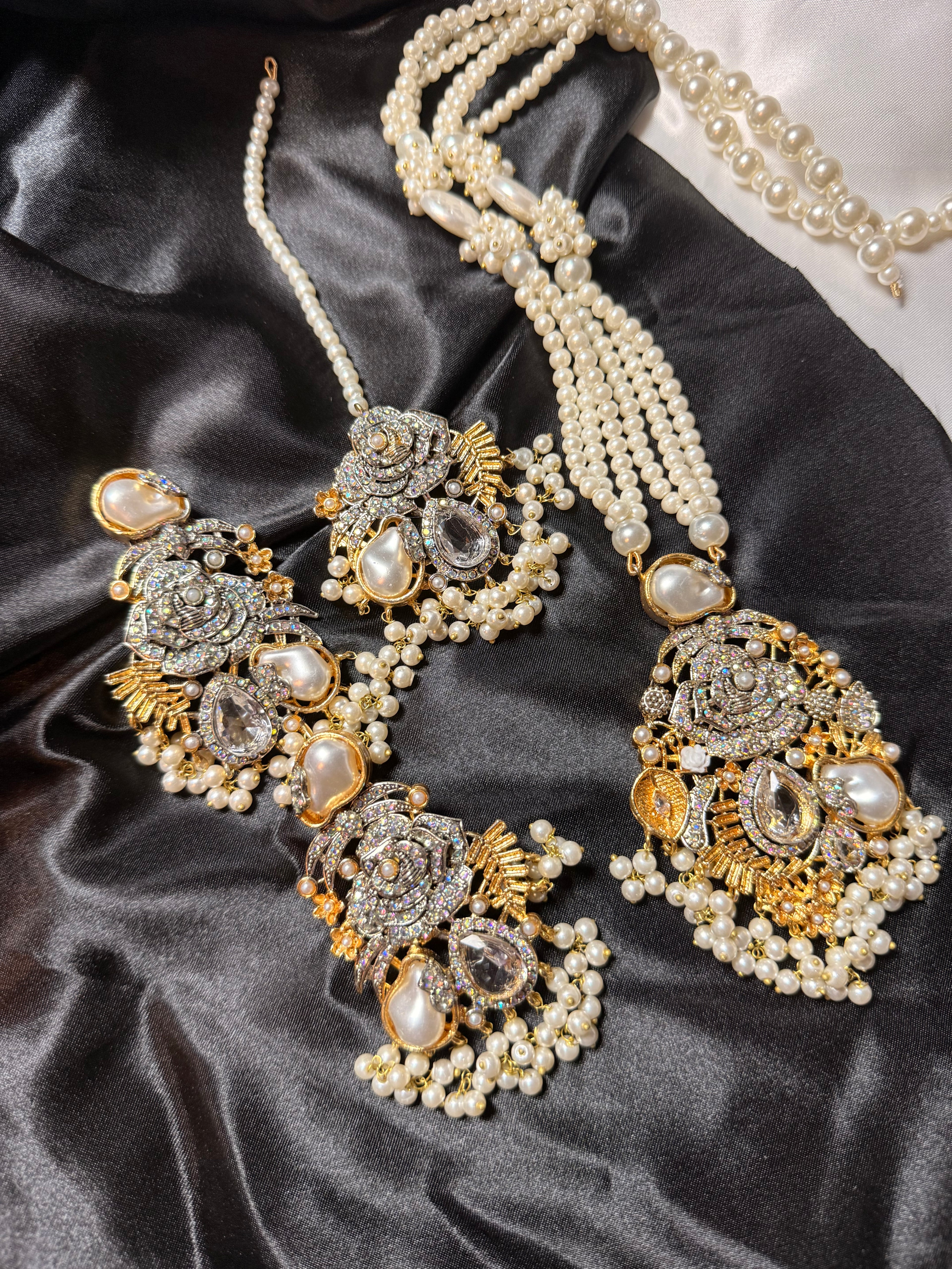 Ornate jewelry set with pearls on a dark satin surface