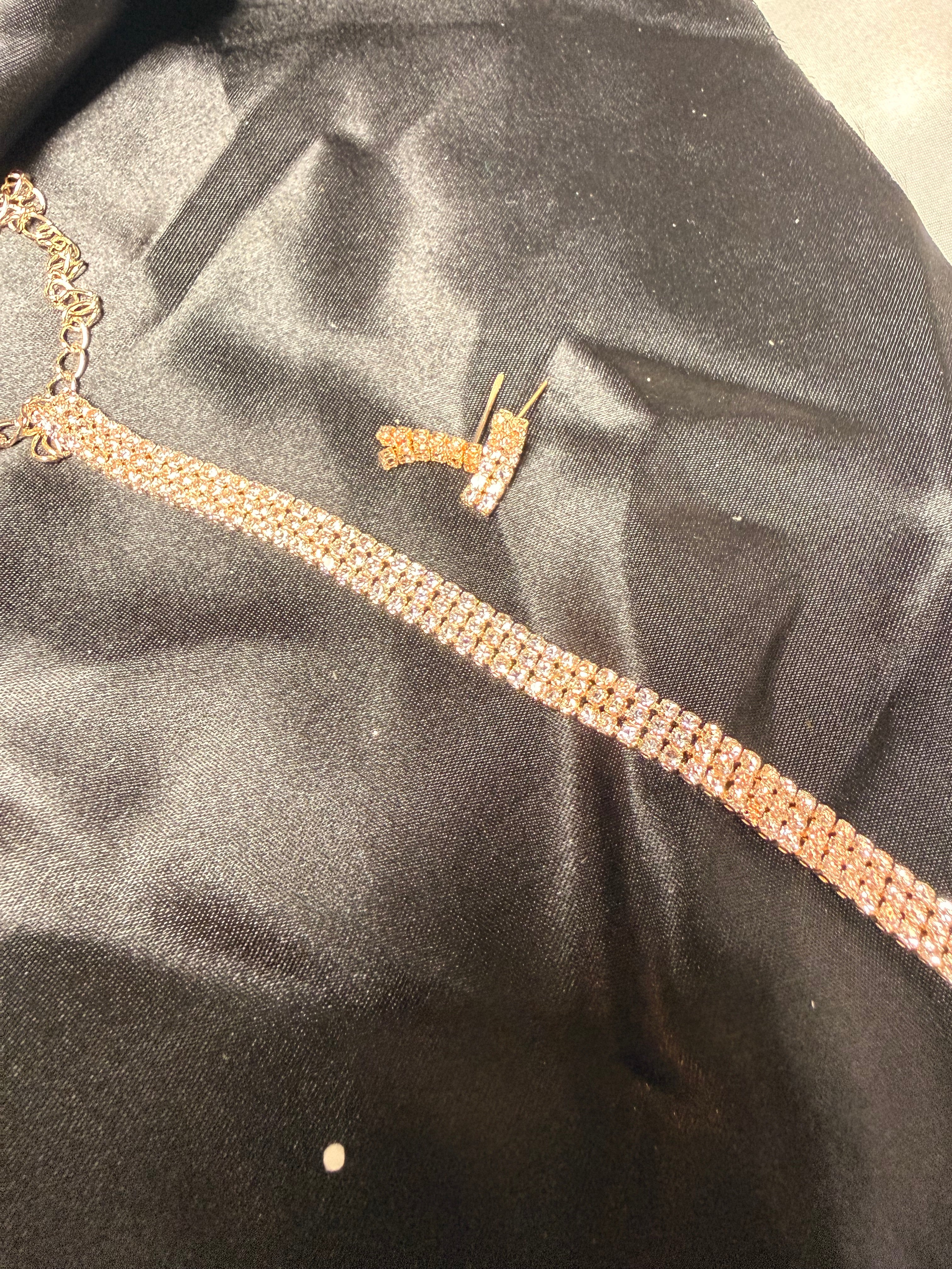 Gold necklace and earrings on a black satin surface