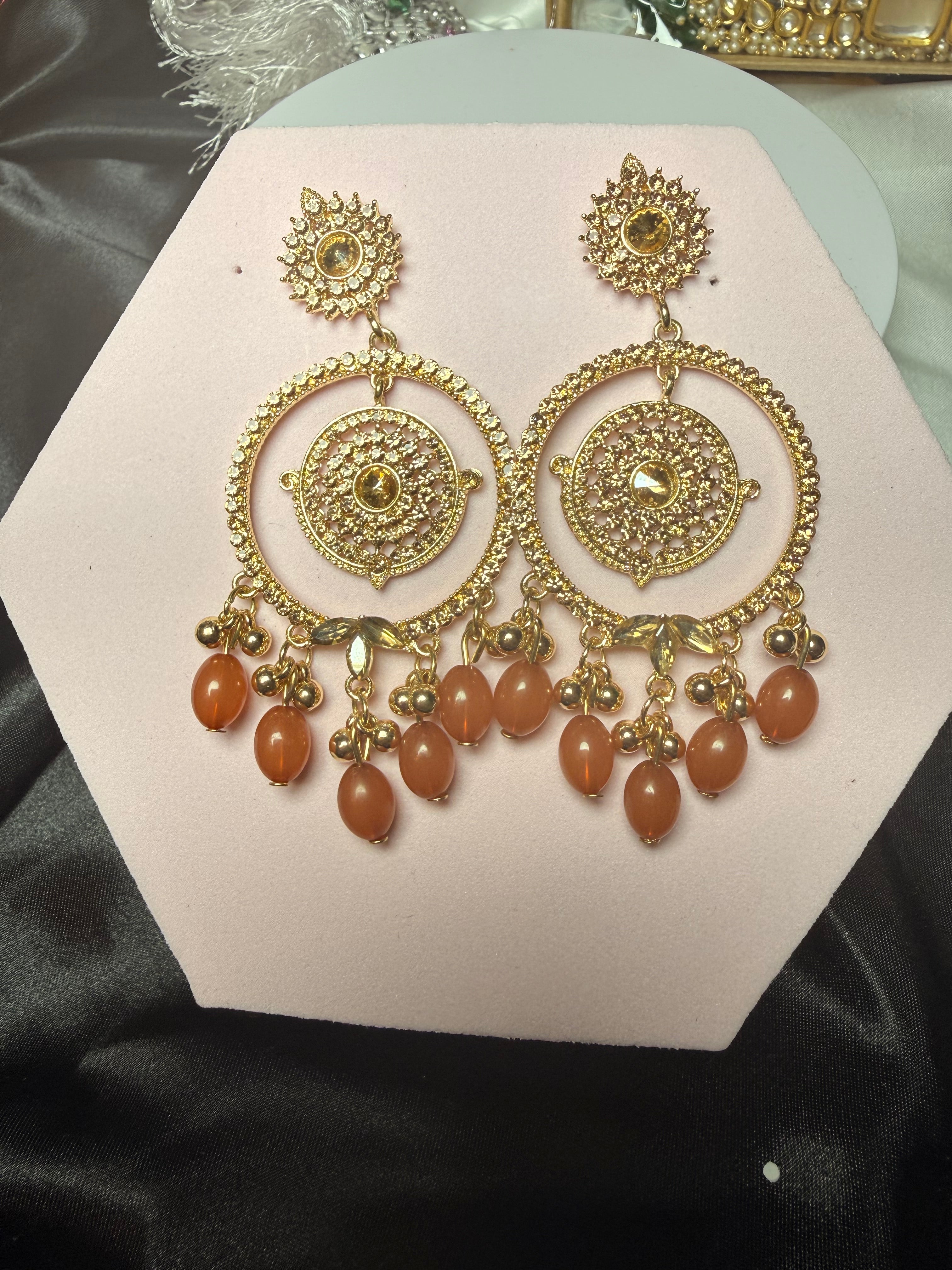Gold and brown jewelry set on a pink hexagonal card