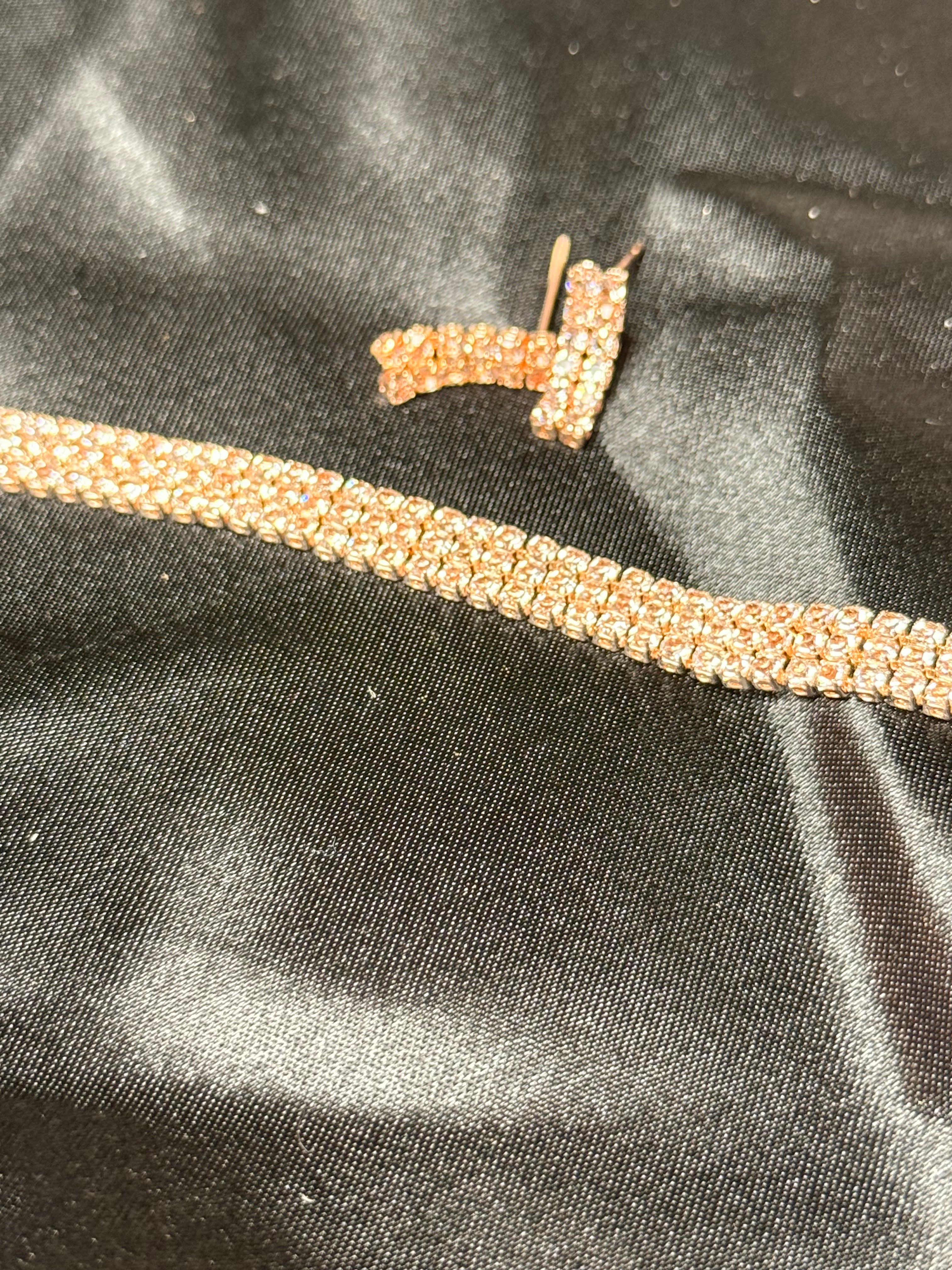 Gold chain with a letter 'T' pendant on a black fabric background