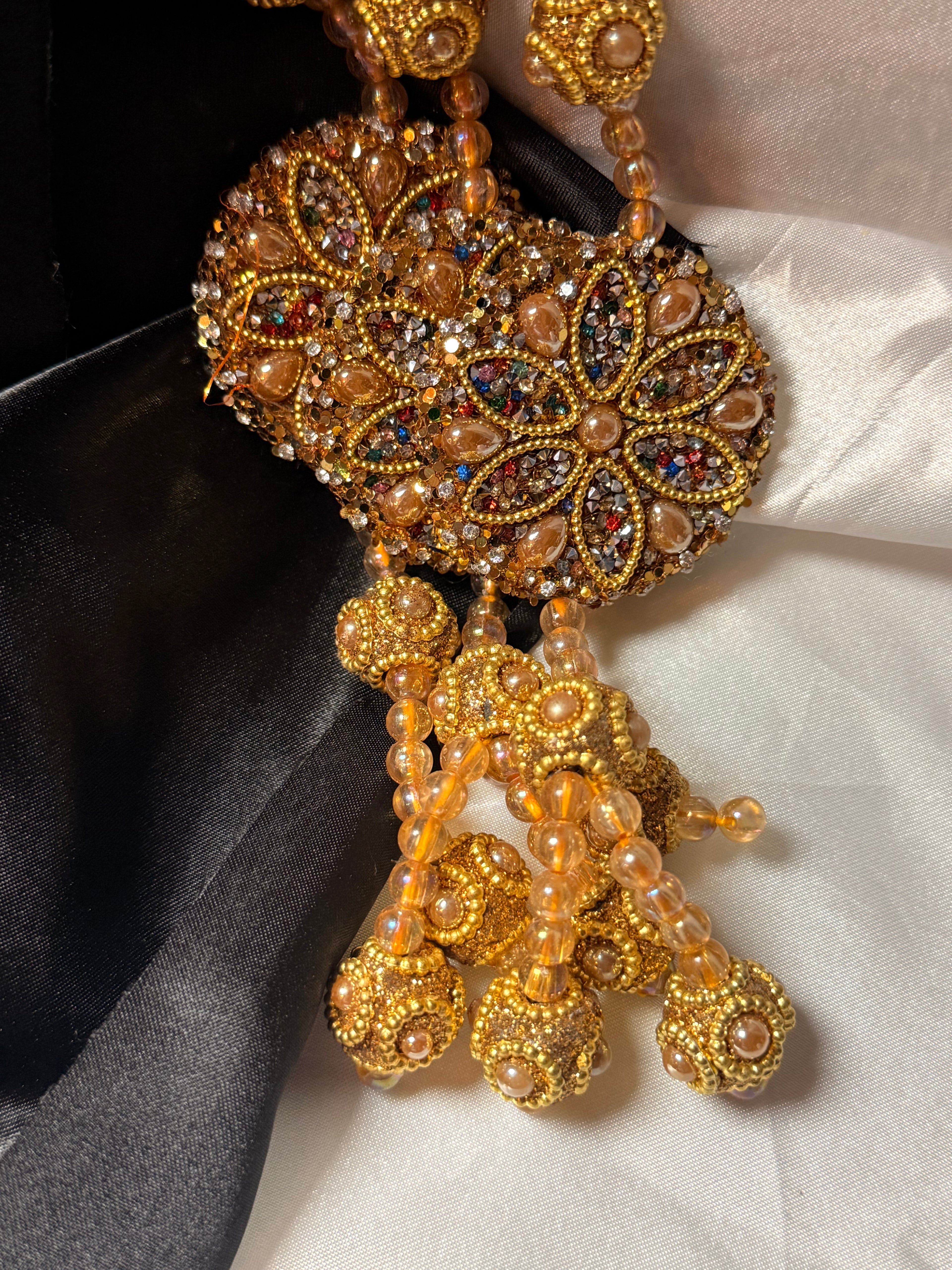 Gold jewelry piece with intricate design on a dark and light fabric background