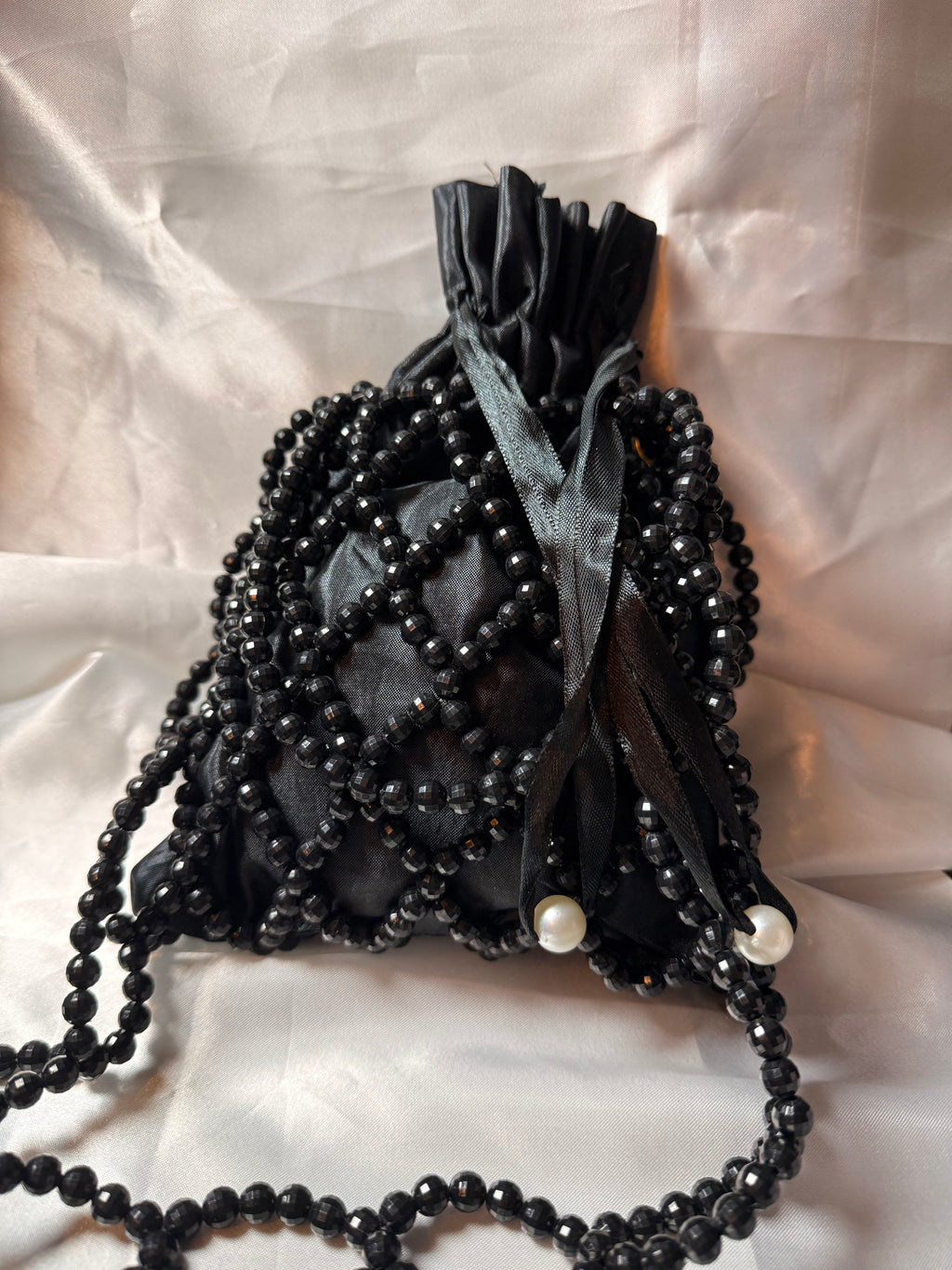 Black beaded bag with pearls on a textured white background