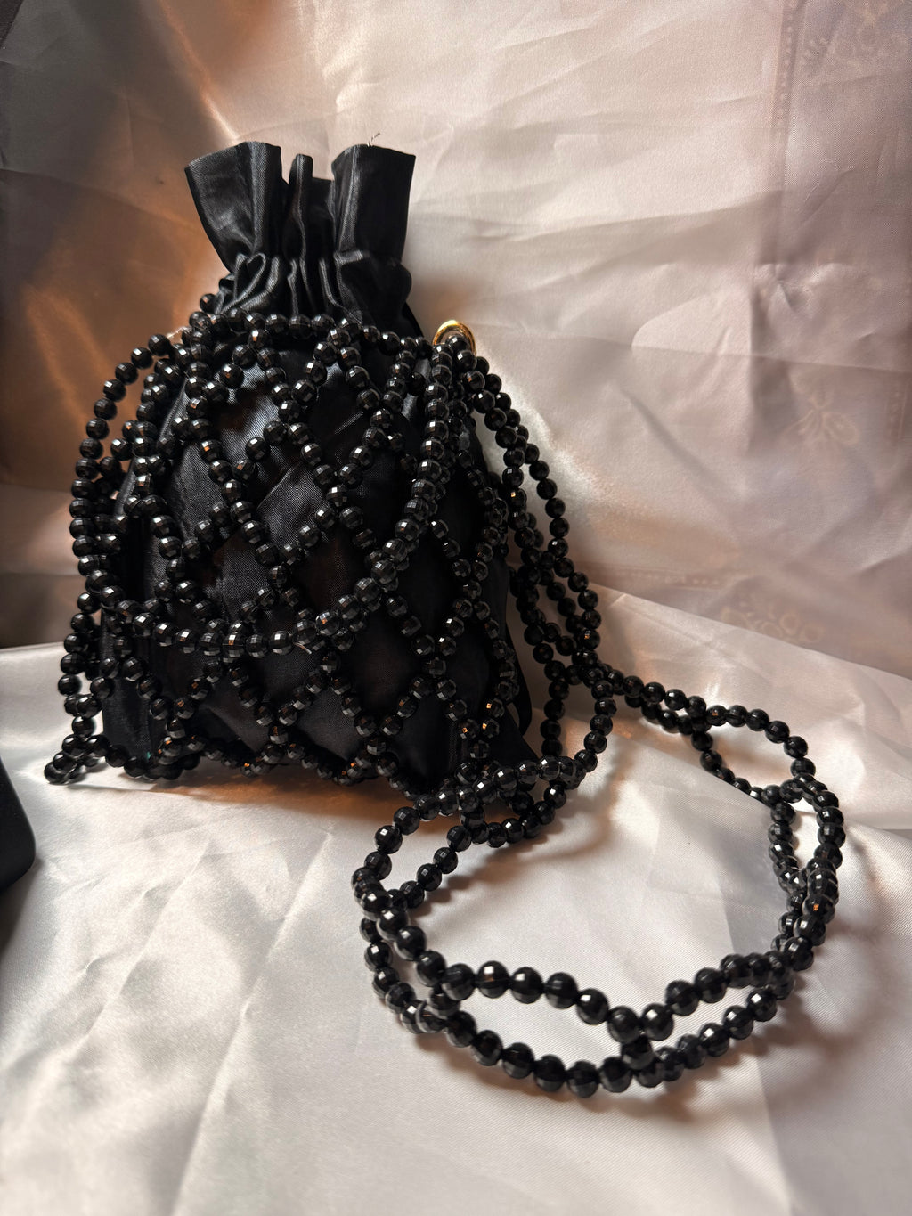 Black beaded handbag on a white fabric background
