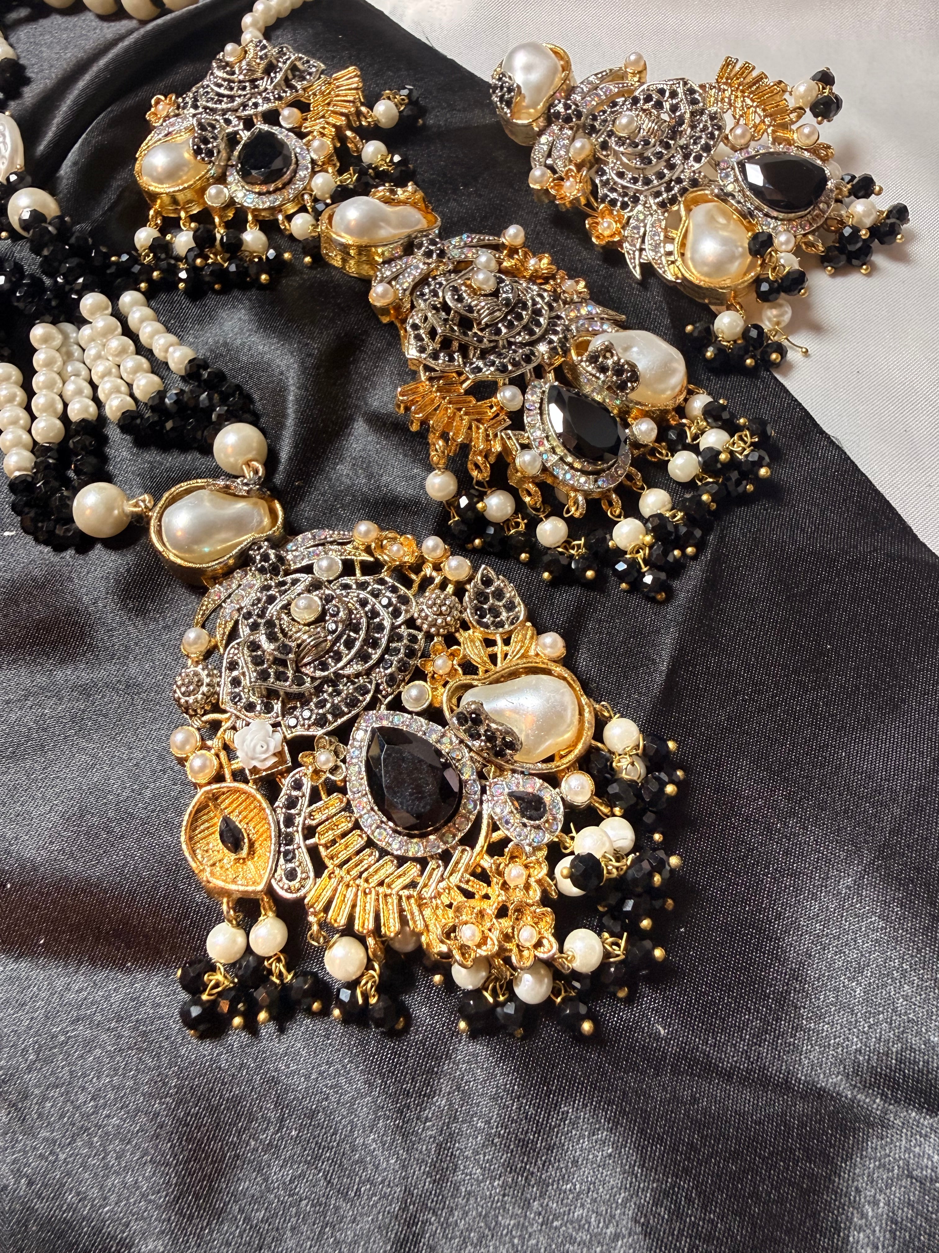 Ornate gold and black jewelry set on a dark fabric background