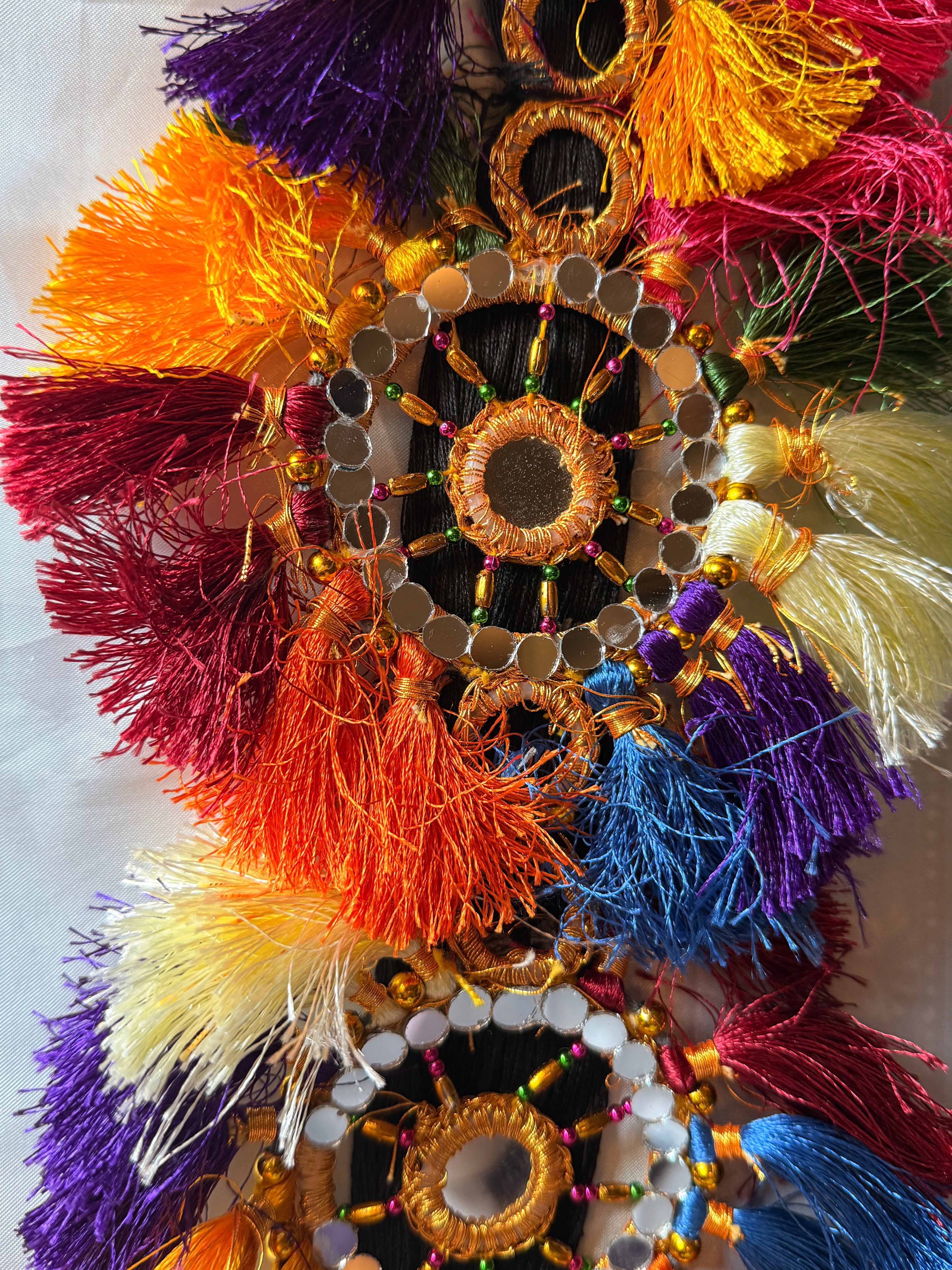 Colorful decorative item with tassels and beads on a light background