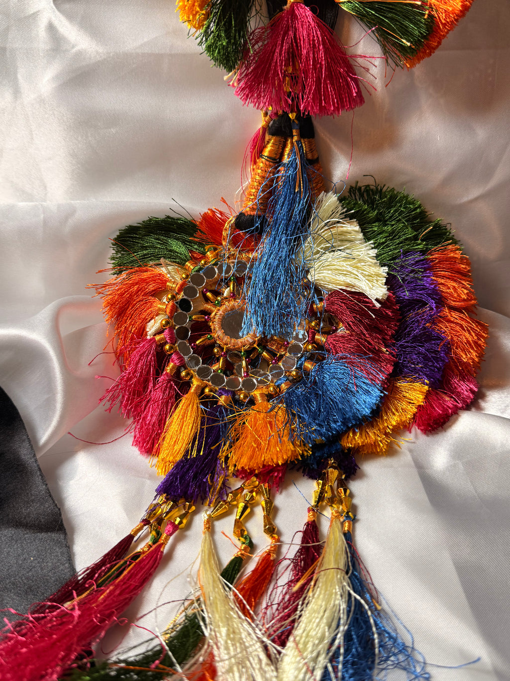 Colorful decorative item with tassels on a white fabric background