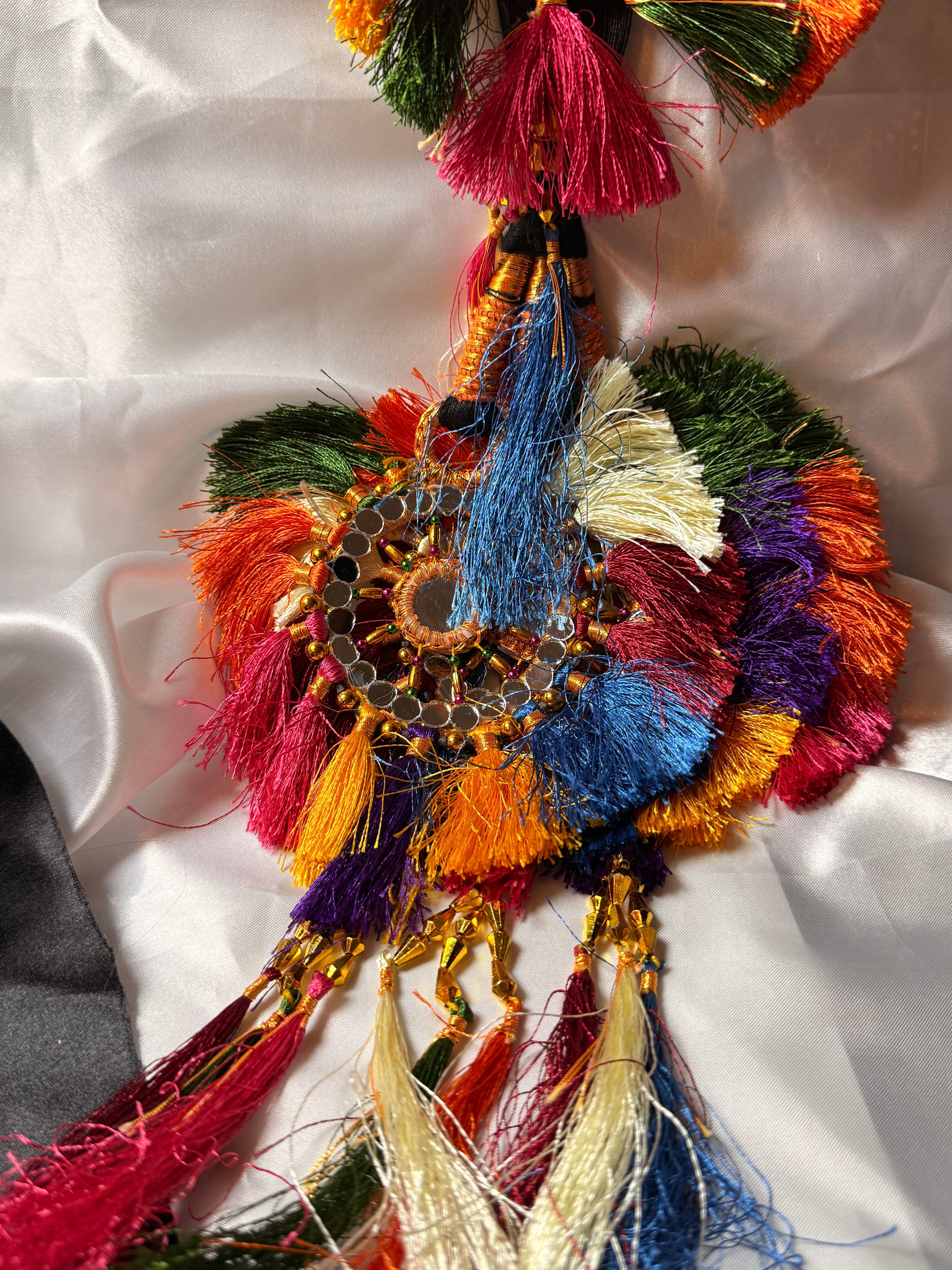 Colorful decorative item with tassels on a white fabric background