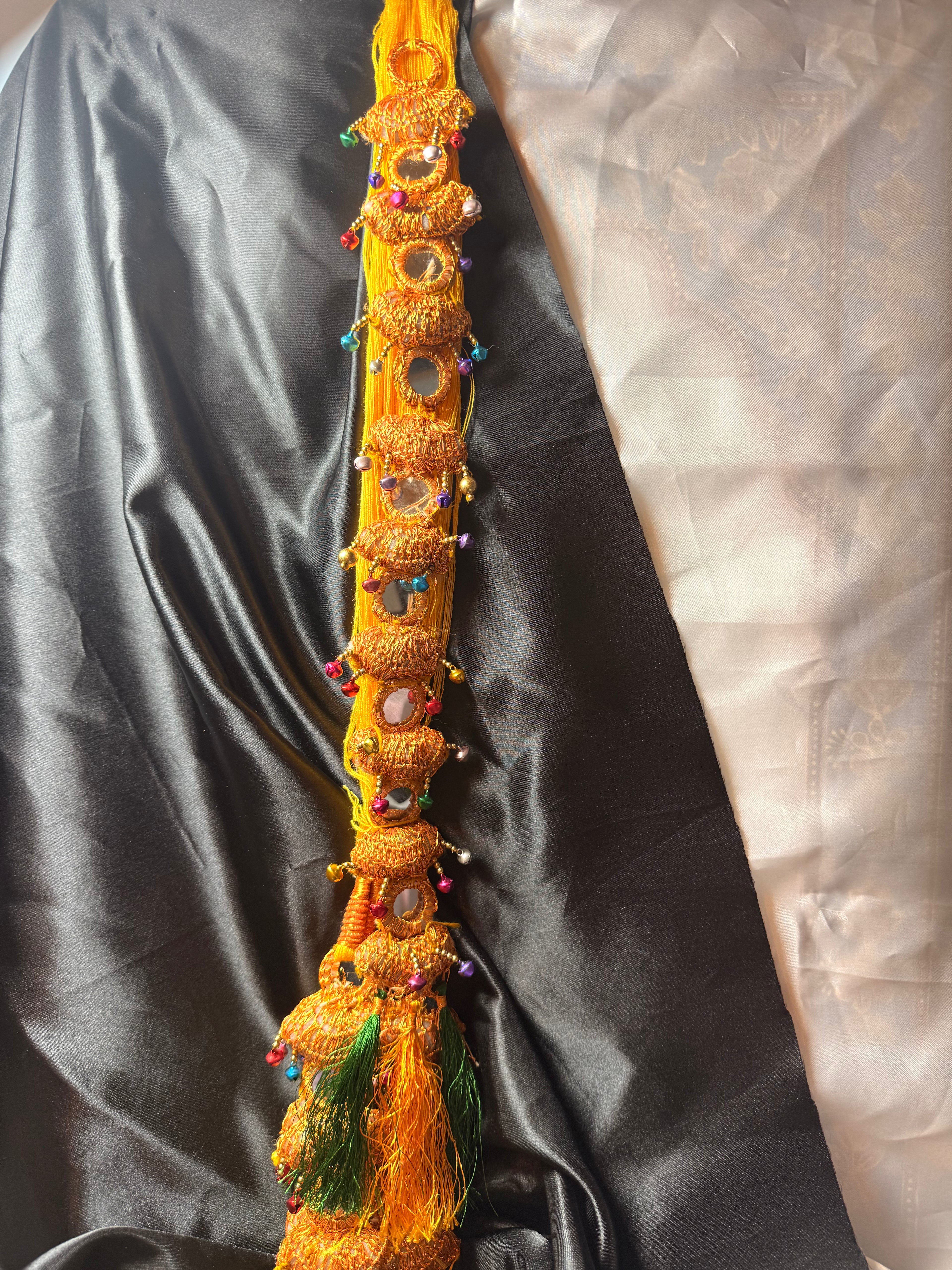 Decorative yellow object with intricate designs on a dark fabric background