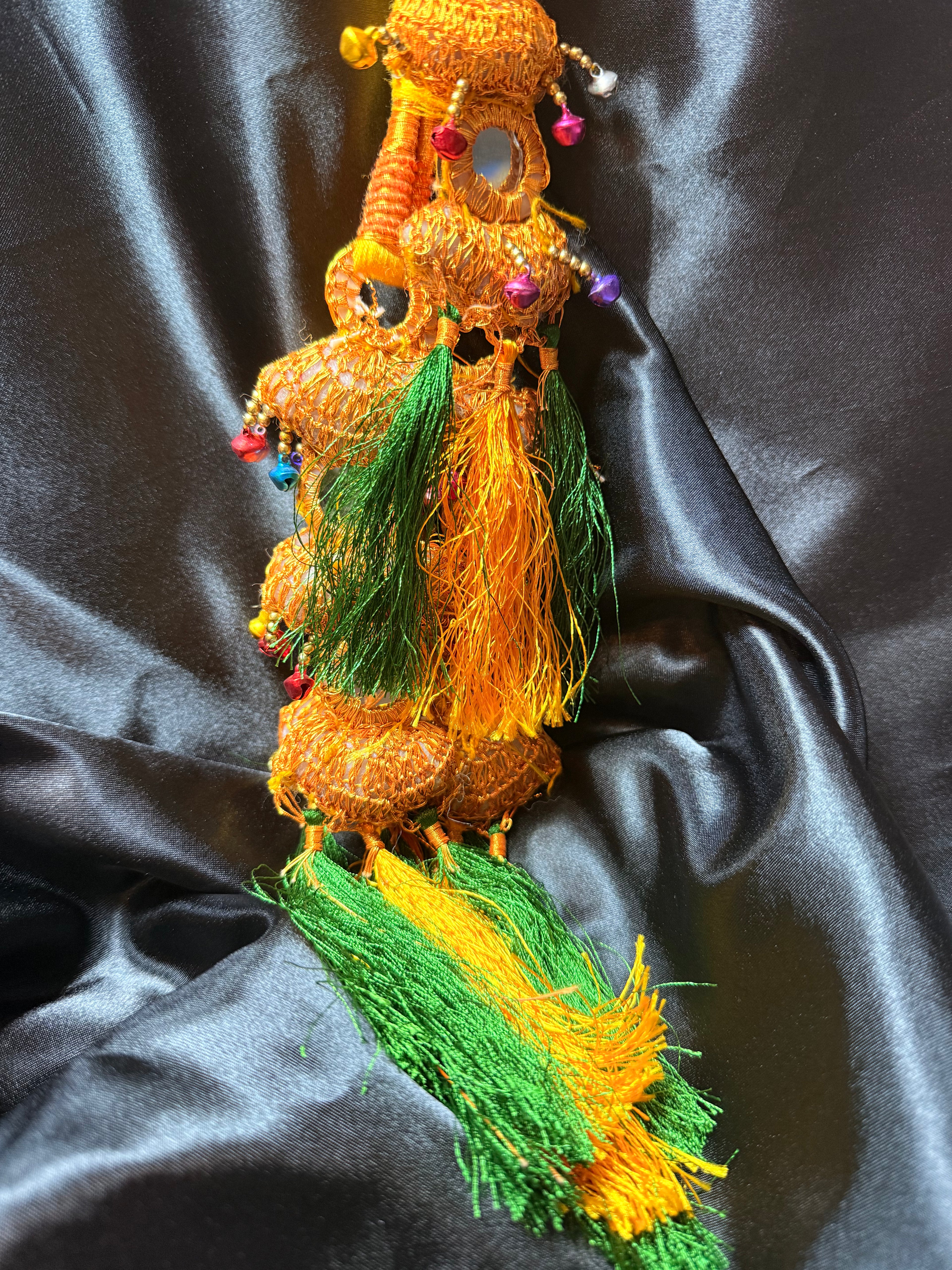 Decorative item with orange and green colors on a dark fabric background