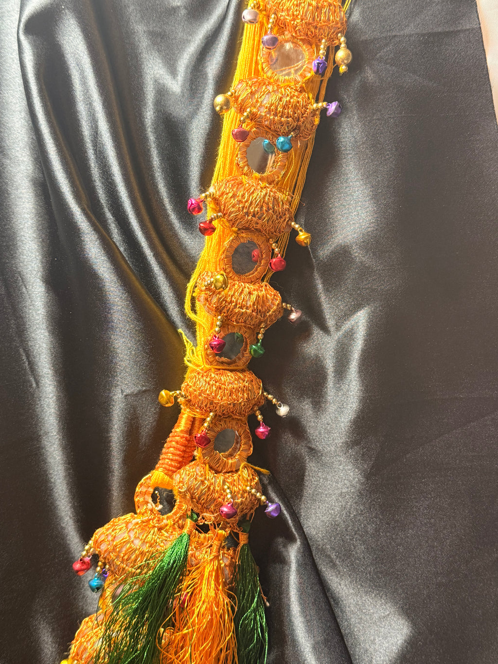 Decorative item with beads and feathers on a dark fabric background