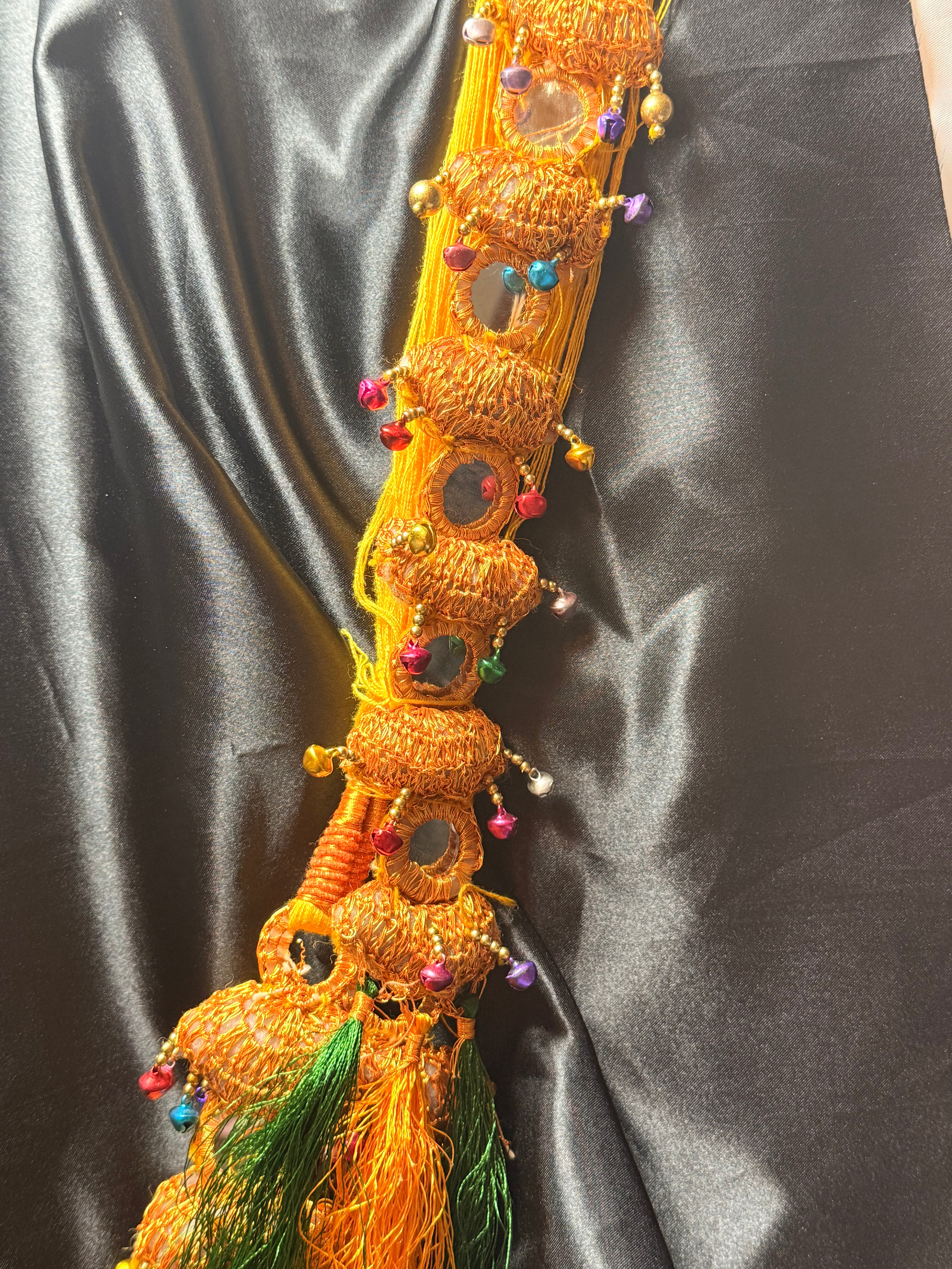Decorative item with beads and feathers on a dark fabric background