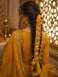 Woman in a yellow traditional outfit with intricate hair accessories in an ornate setting.