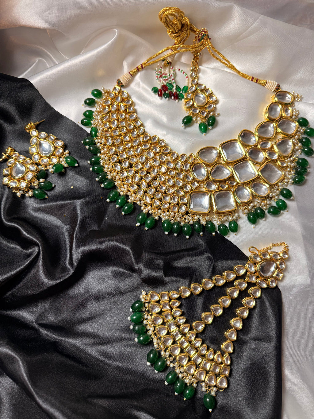 Gold and green jewelry set on a satin fabric background