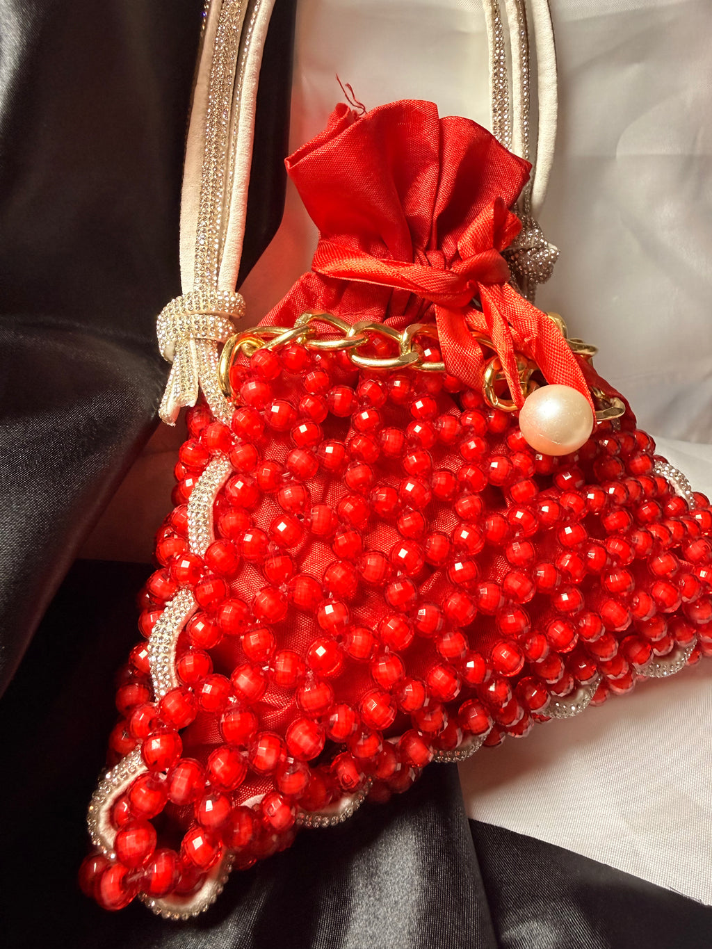 Red beaded handbag with gold accents on a dark fabric background