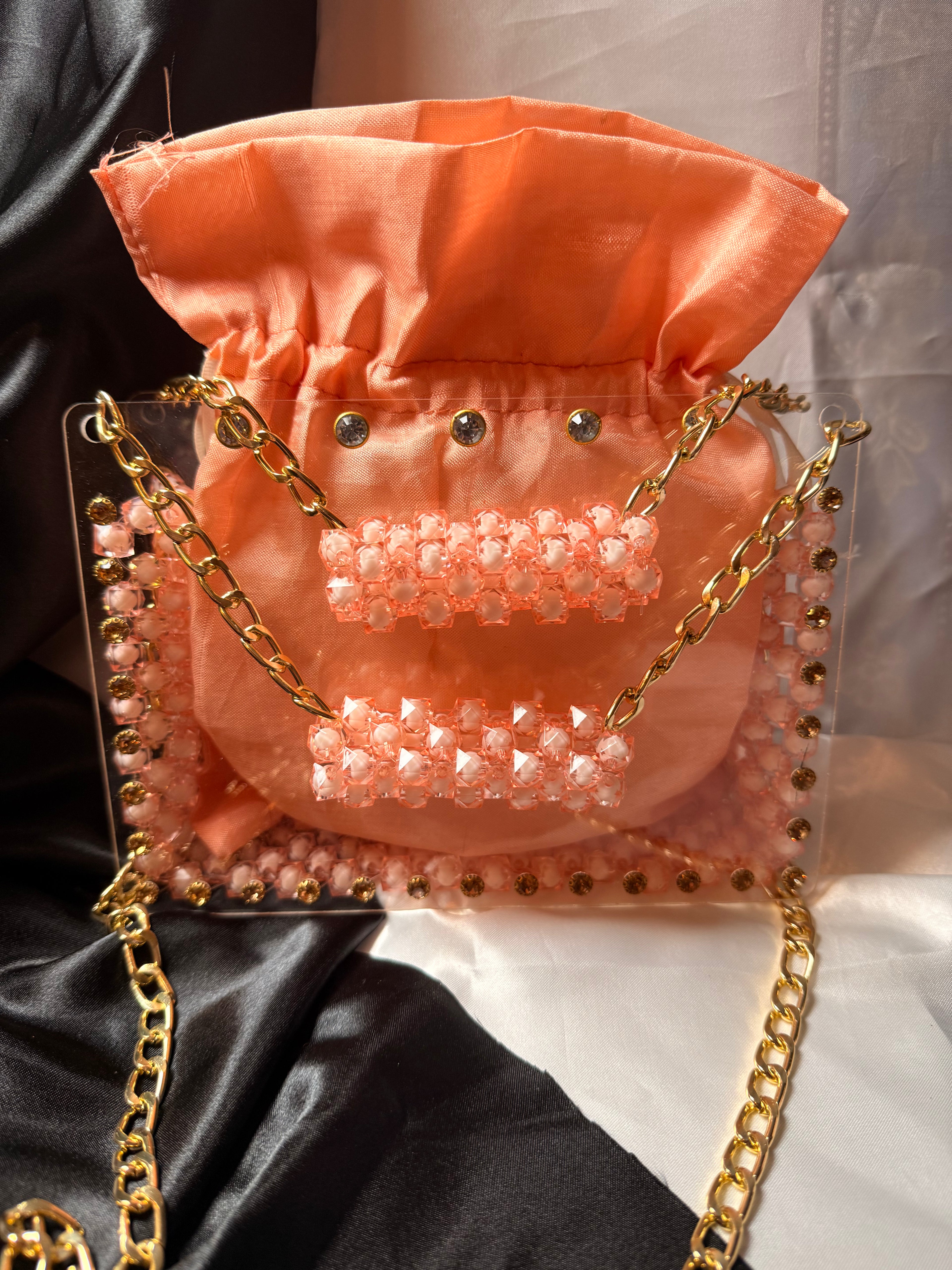 Pink handbag with gold chain strap on a black and white background