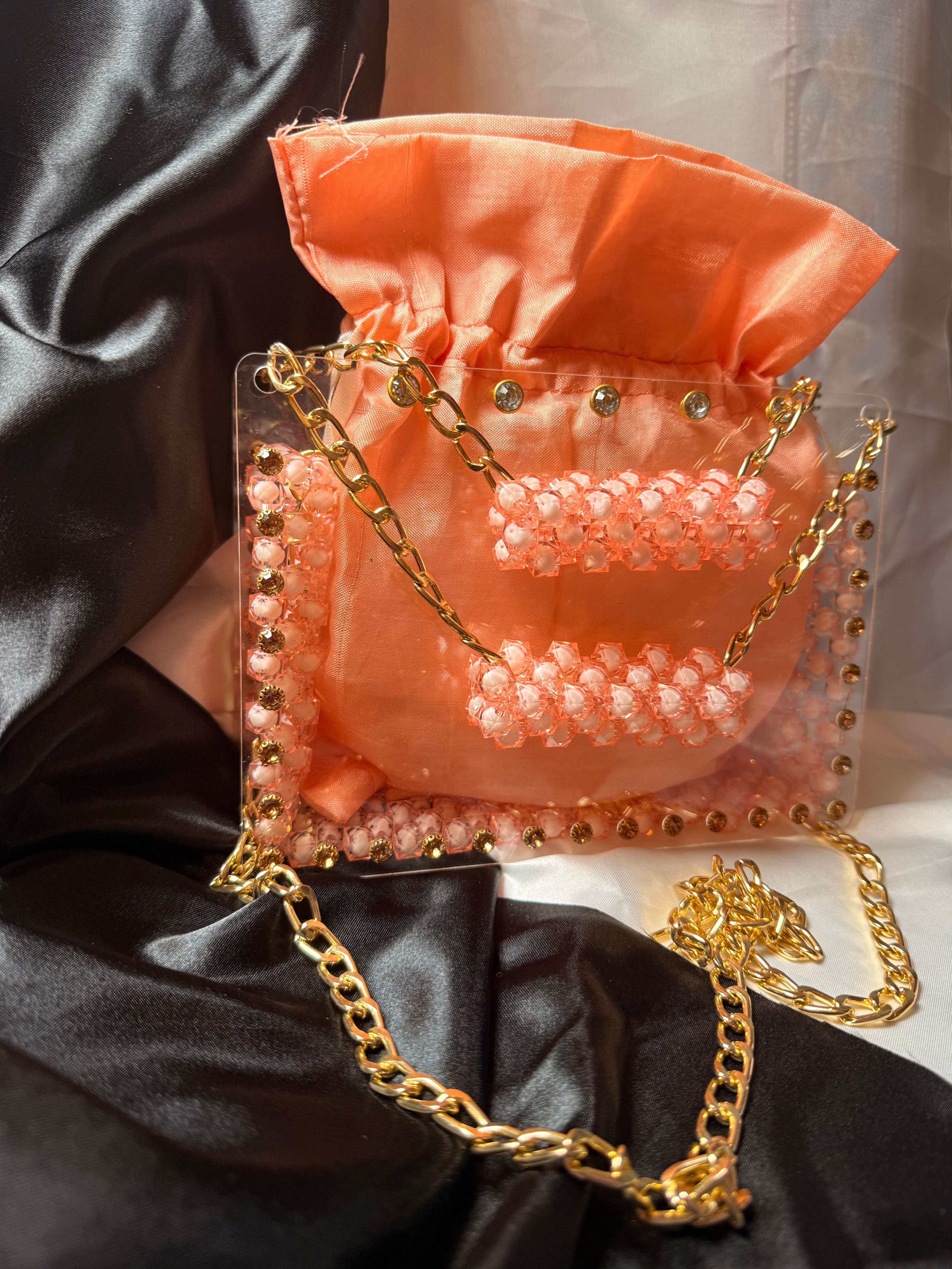 Orange handbag with gold chain strap on a black and white fabric background
