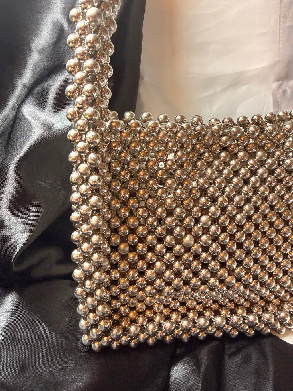 Close-up of a beaded clutch bag on a black satin surface