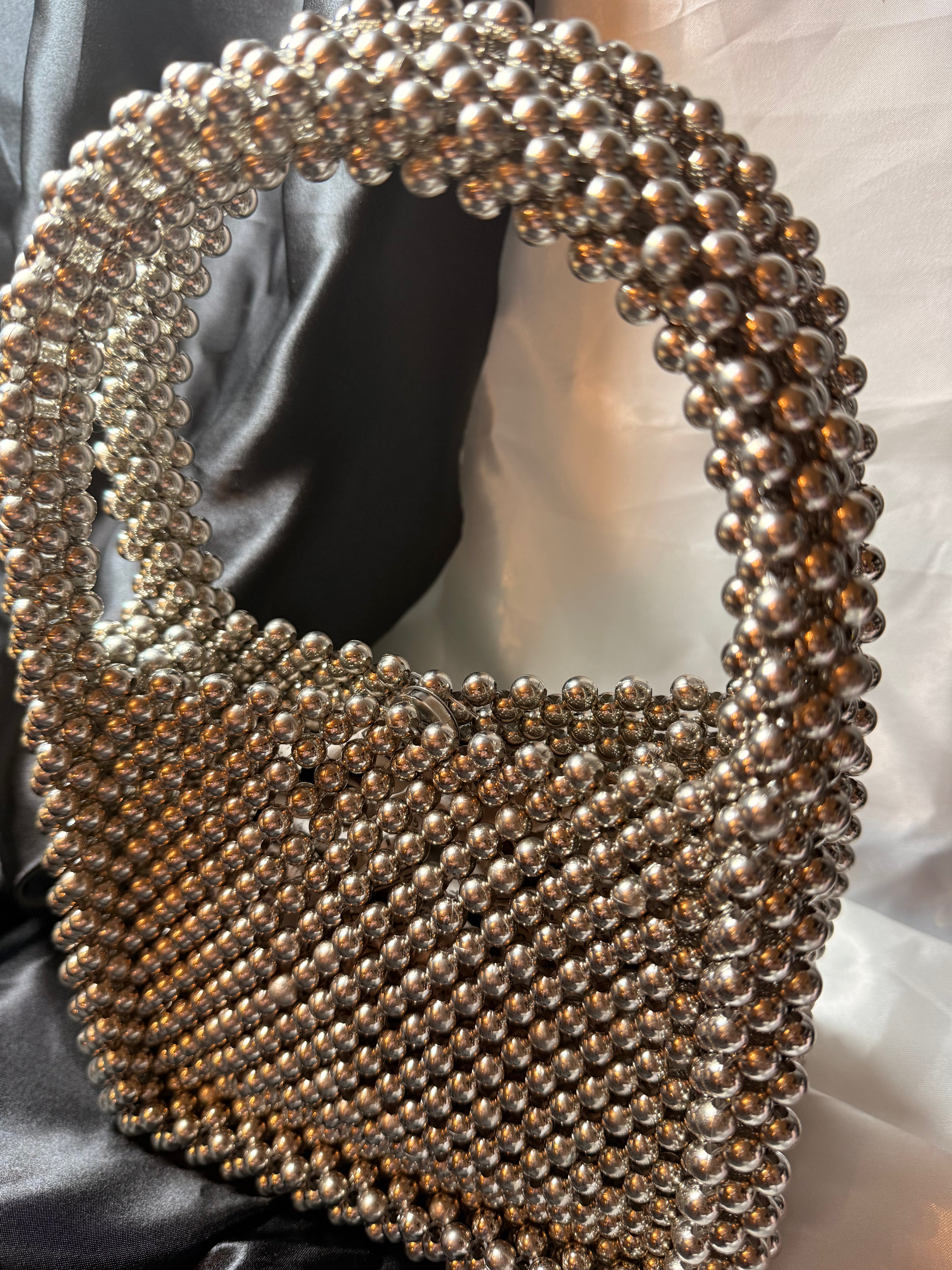 Silver beaded handbag on a satin surface