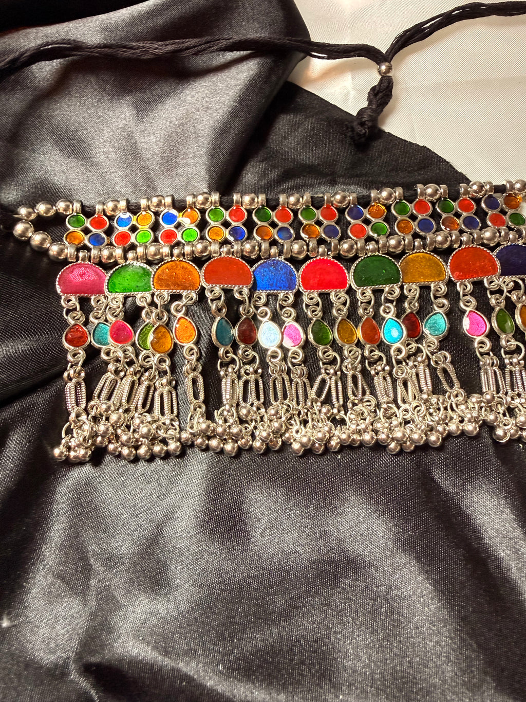 Decorative belt with colorful beads and silver accents on a black satin background