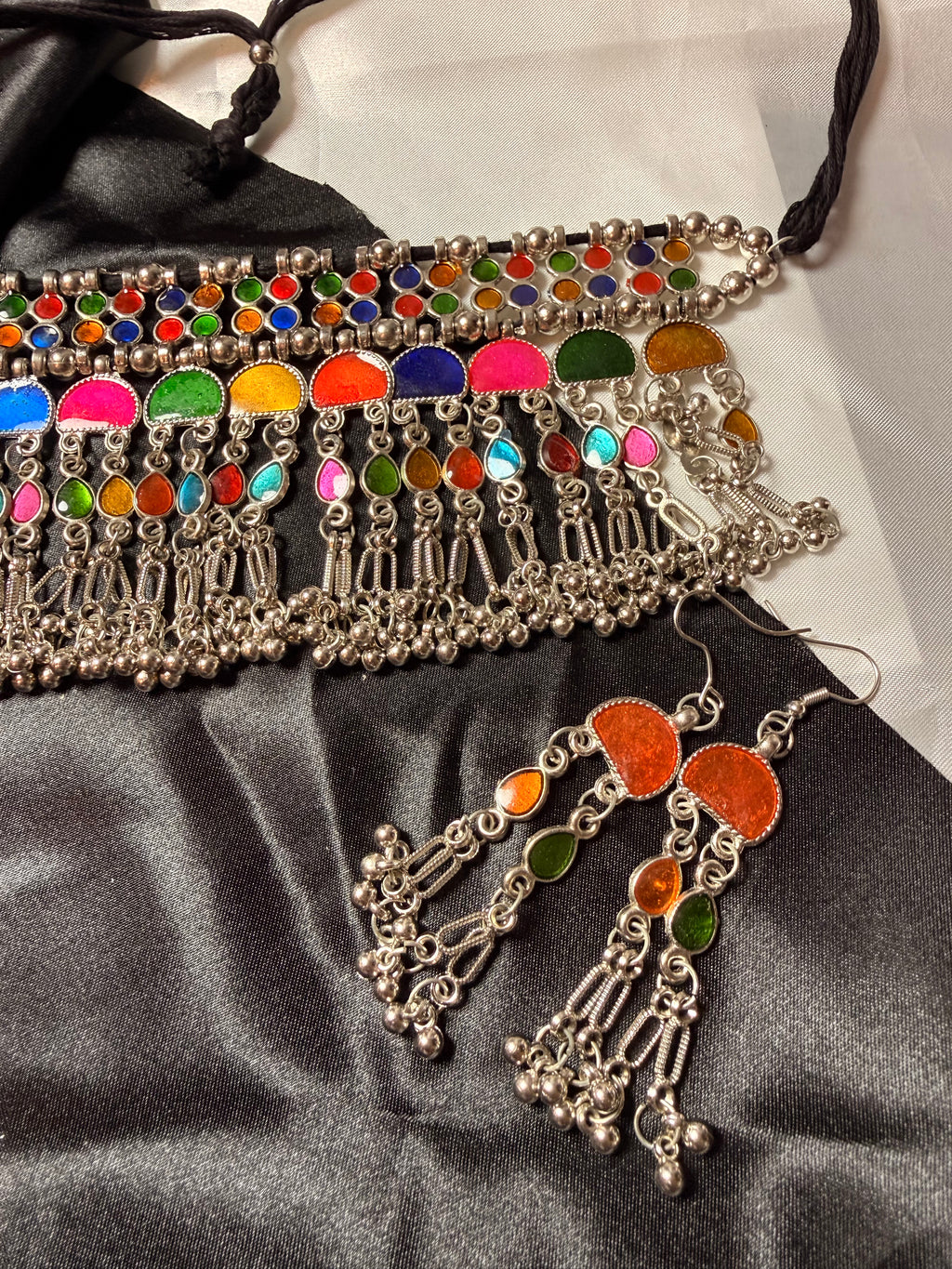 Colorful beaded belt and earrings on a black satin surface