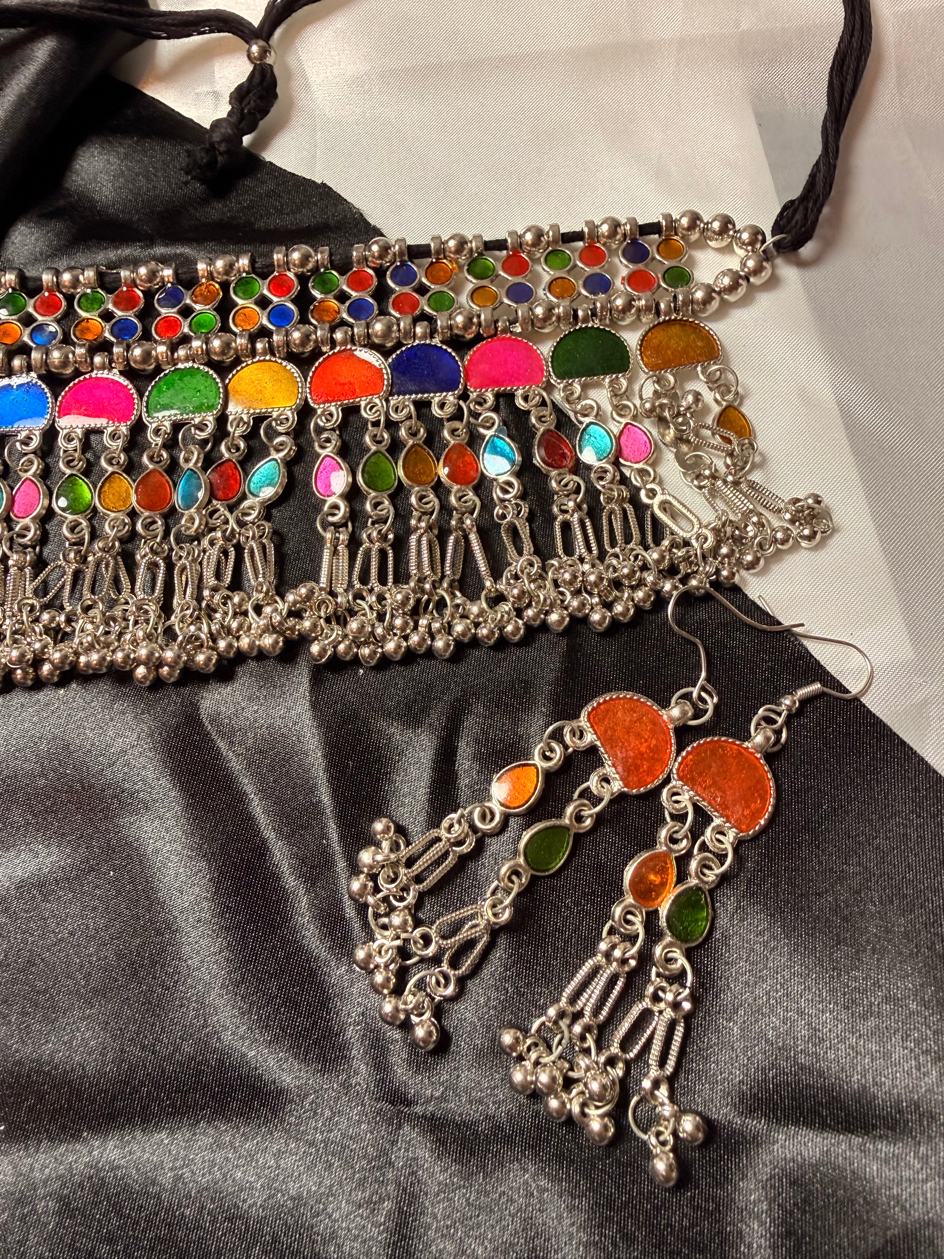 Colorful beaded belt and earrings on a black satin surface