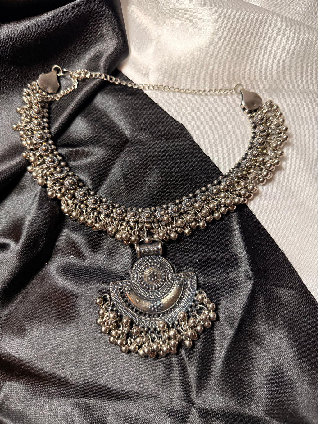 Decorative necklace with intricate design on a black satin surface