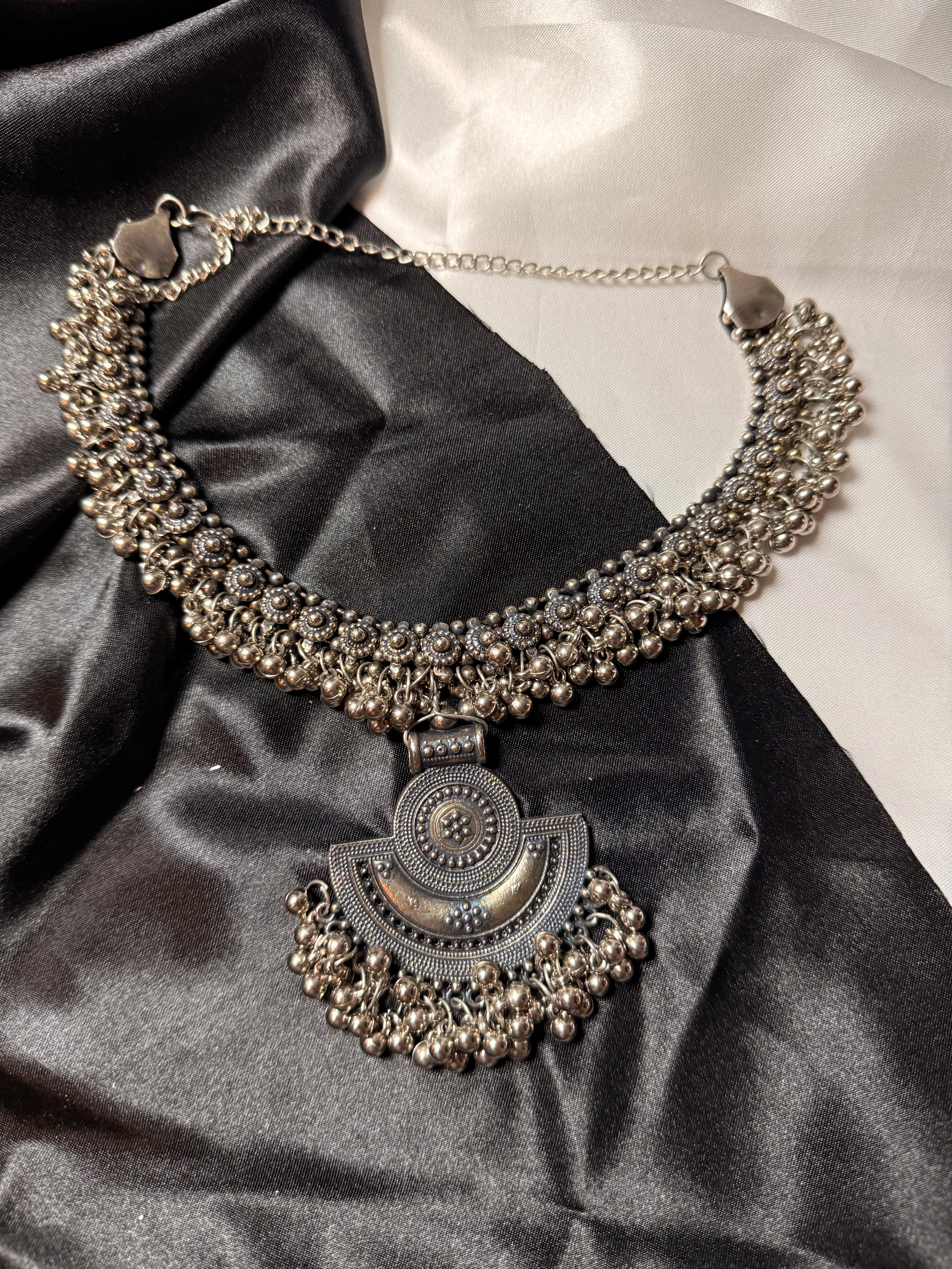 Decorative necklace with intricate design on a black satin surface