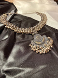 Silver necklace with intricate design on a black satin fabric