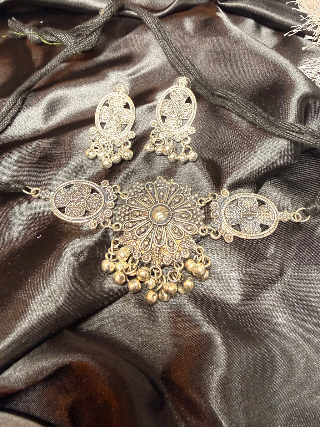 Gold necklace and earrings on a dark satin fabric