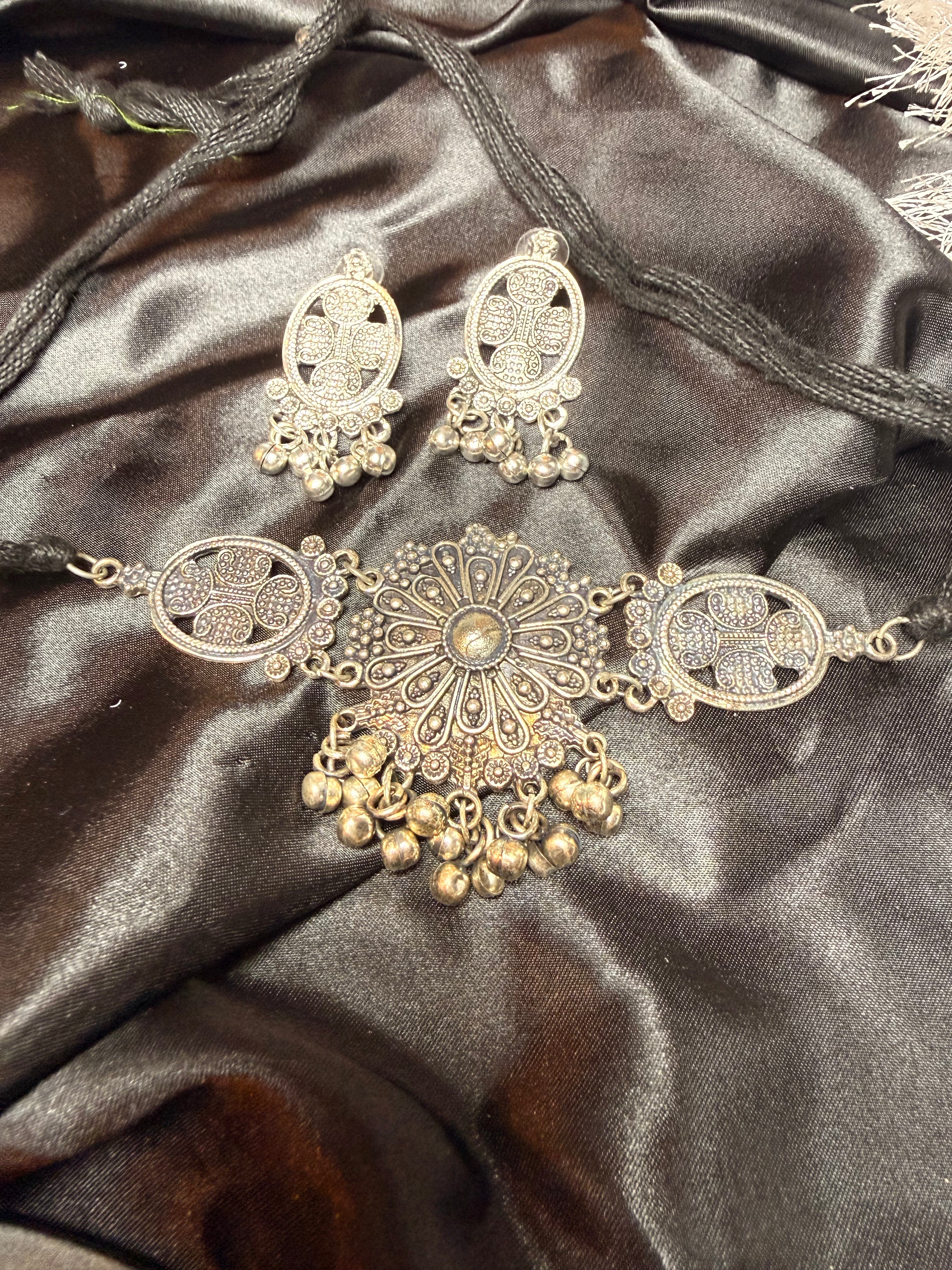 Gold necklace and earrings on a dark satin fabric