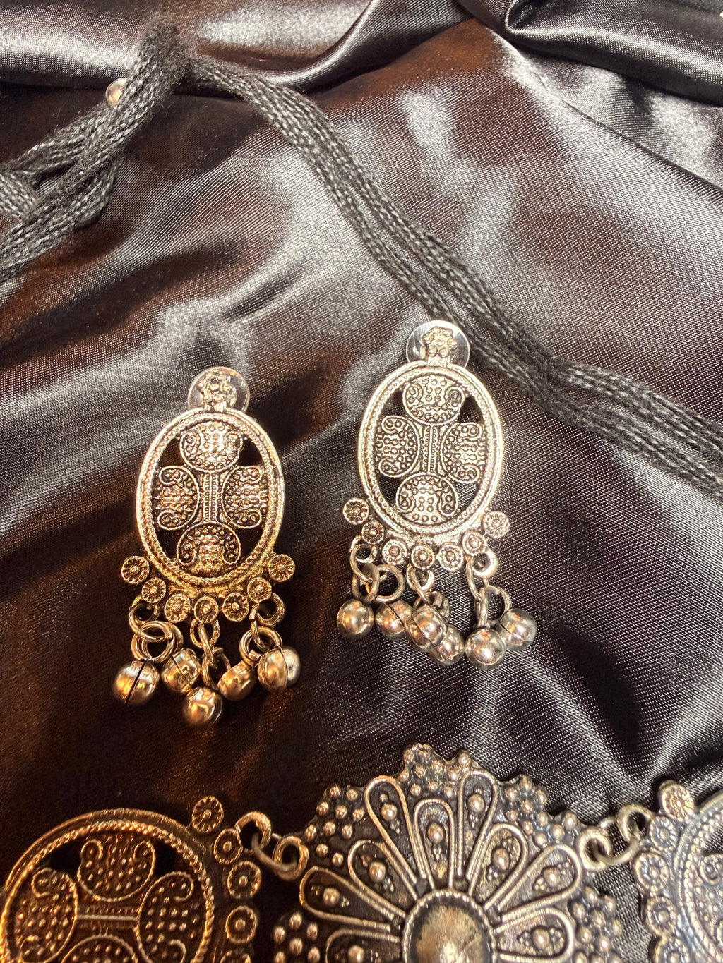 Ornate gold earrings on a dark fabric background