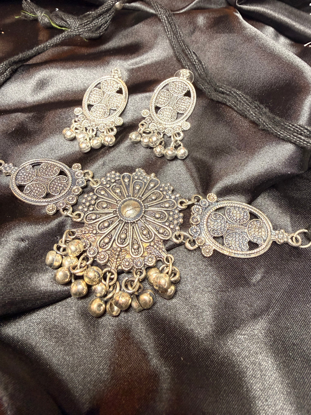 Decorative silver and gold jewelry set on a dark satin surface