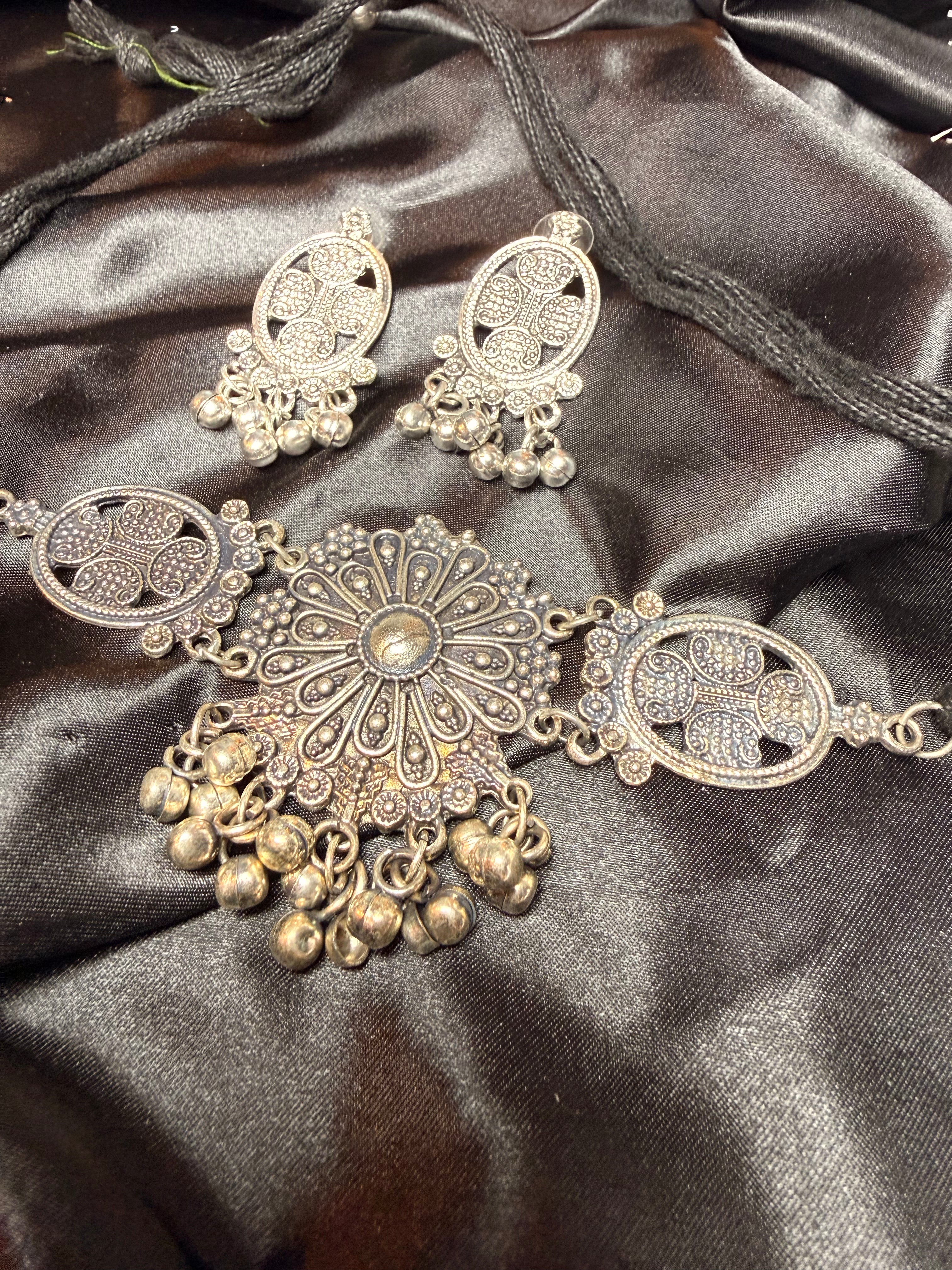 Decorative silver and gold jewelry set on a dark satin surface