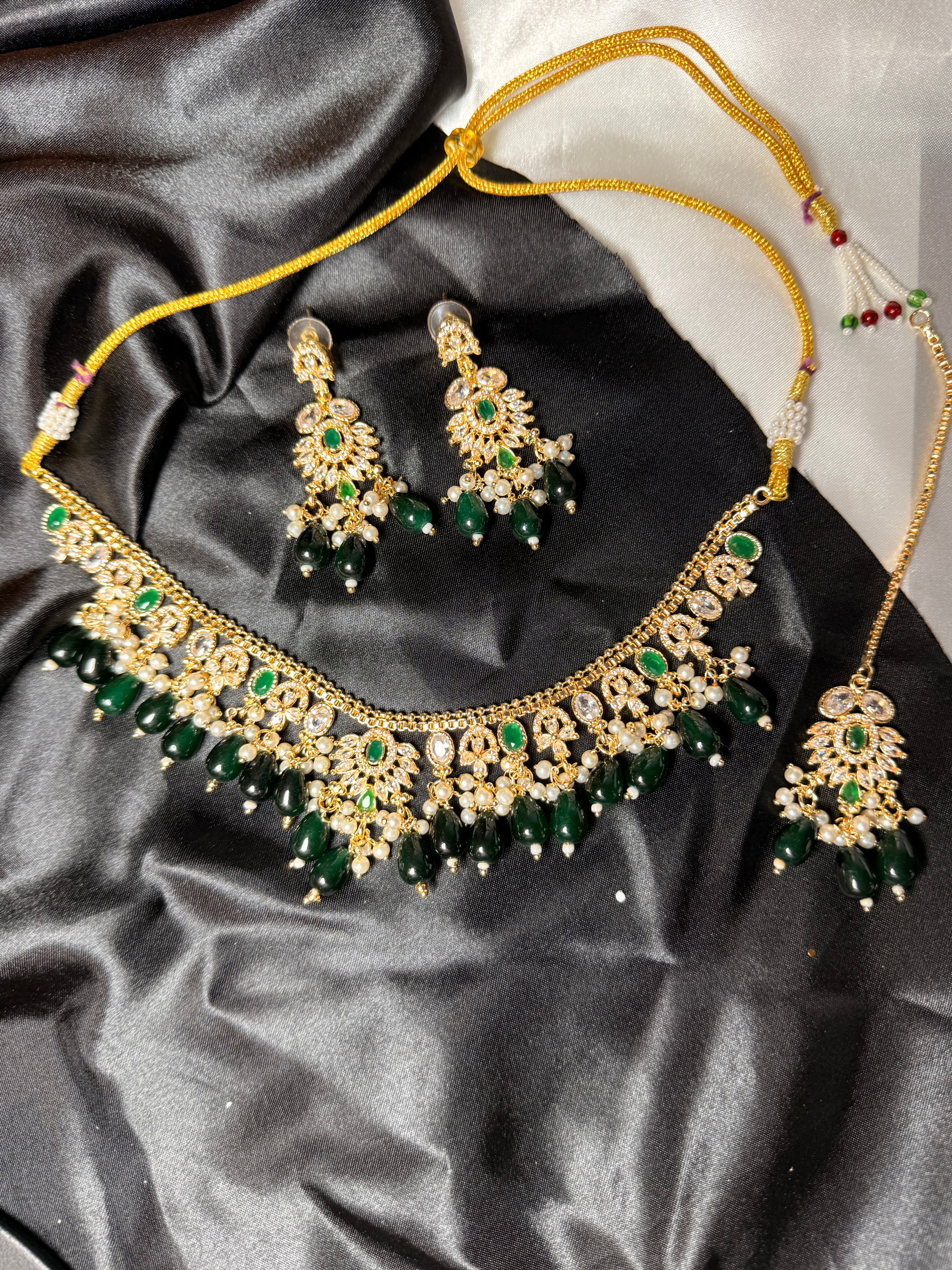 Gold and green jewelry set on a black satin background